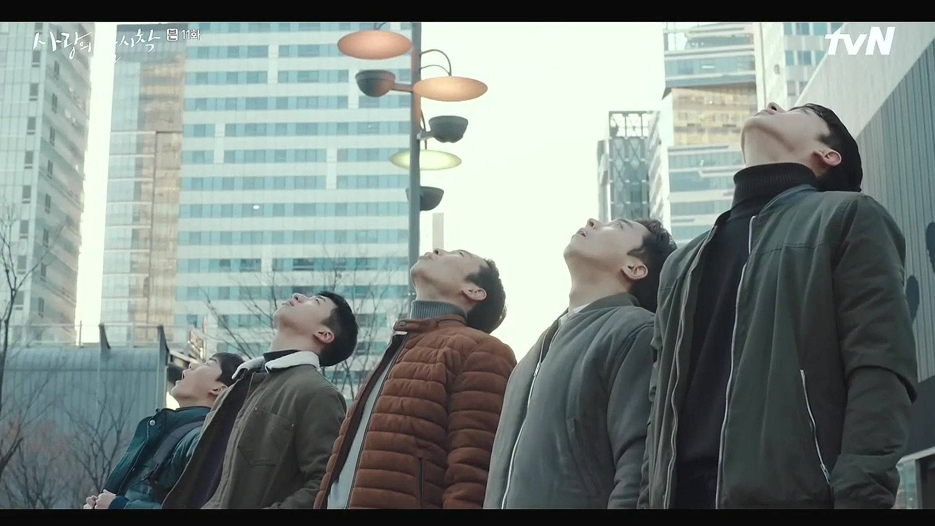 drama 桌布 壁紙 — 四個穿著都市外套的男人在現代建築和禿樹的城市景觀中仰望，天空多雲。
