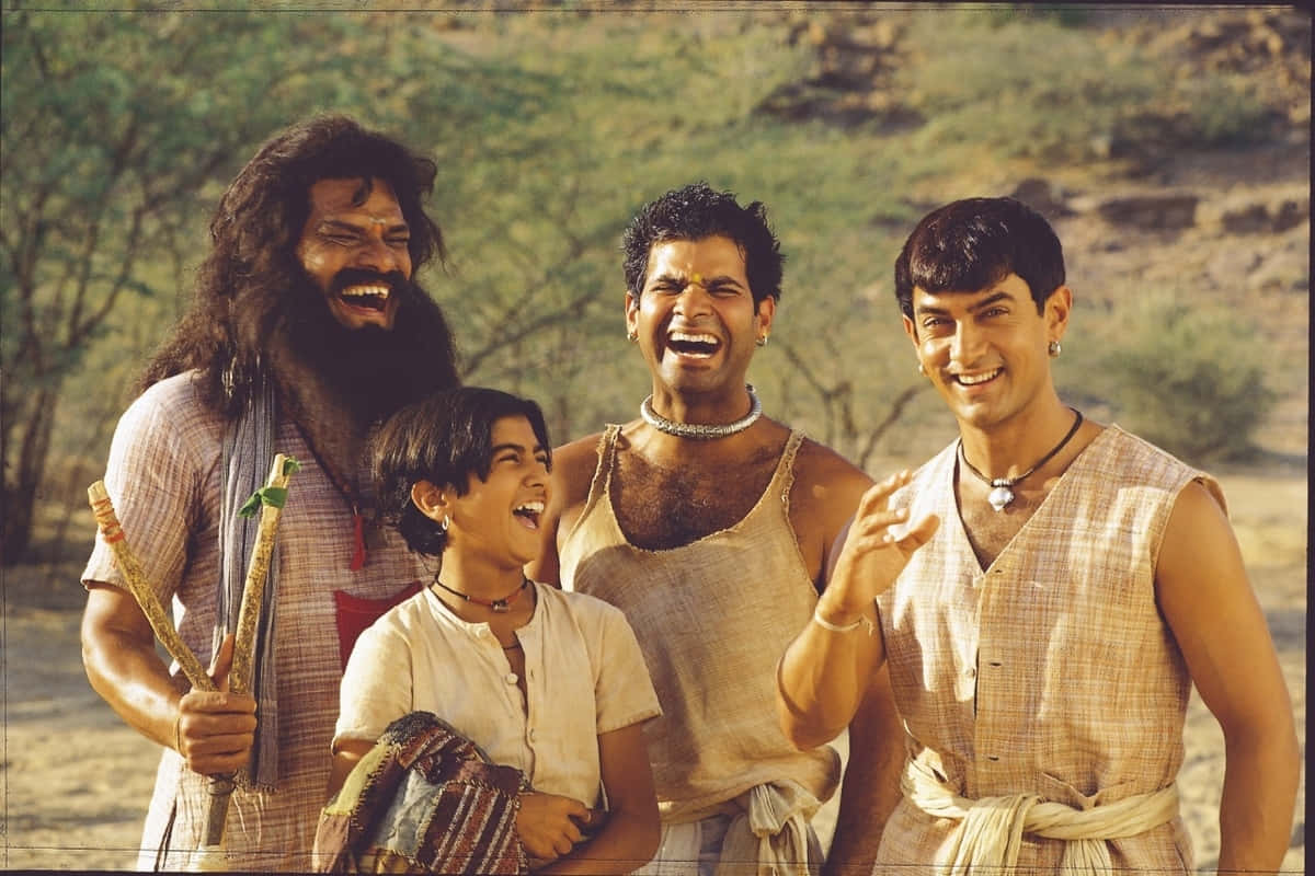 Aamir Khan 桌布 壁紙 — 四個穿著鄉村服裝的快樂男人在陽光明媚的乾旱景觀中開懷大笑，樹木稀疏。