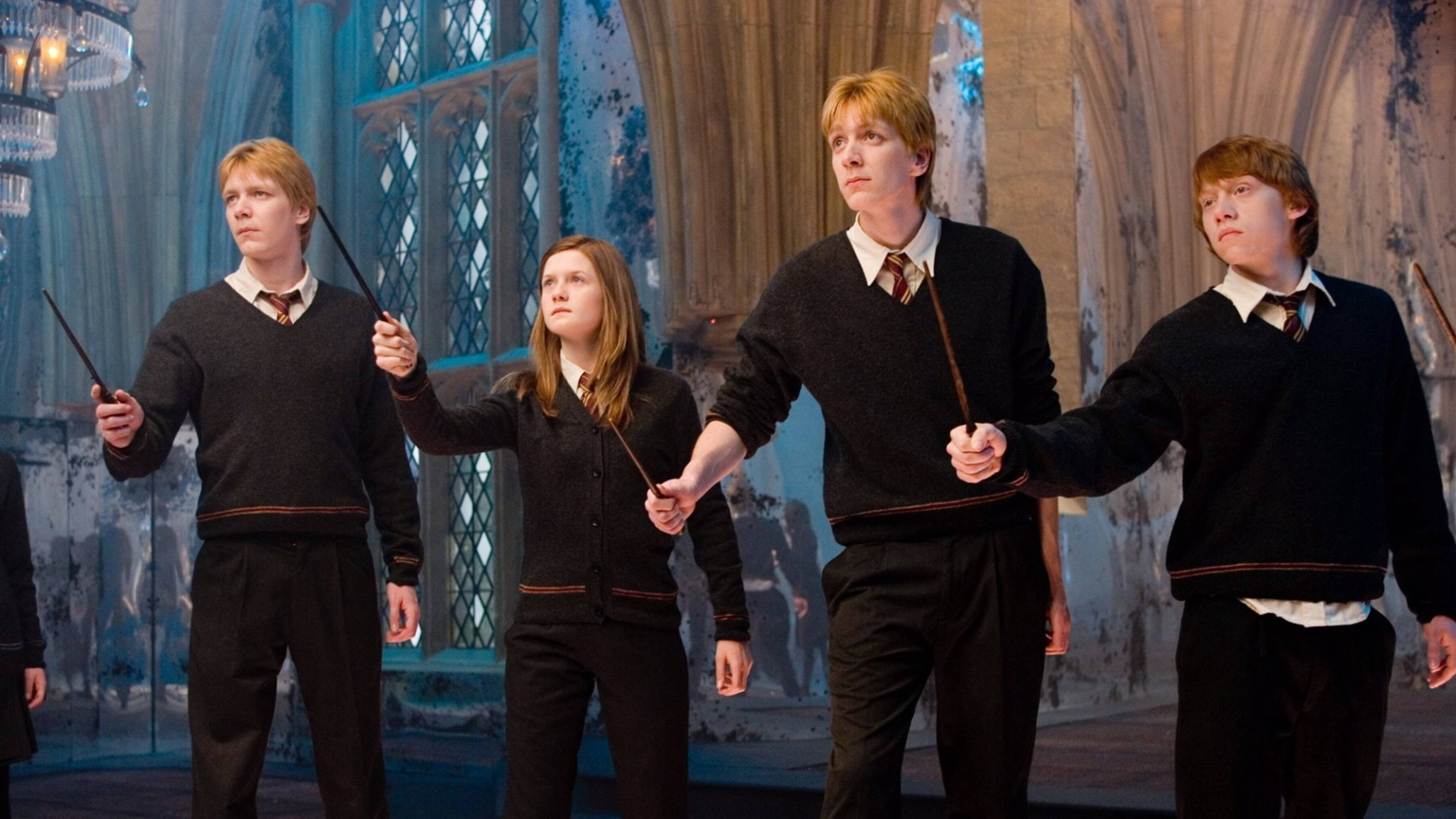 Ron Weasley 桌布 壁紙 — 四個穿著霍格華茲校服的學生站在宏偉的大廳中，手持魔杖，神情專注。