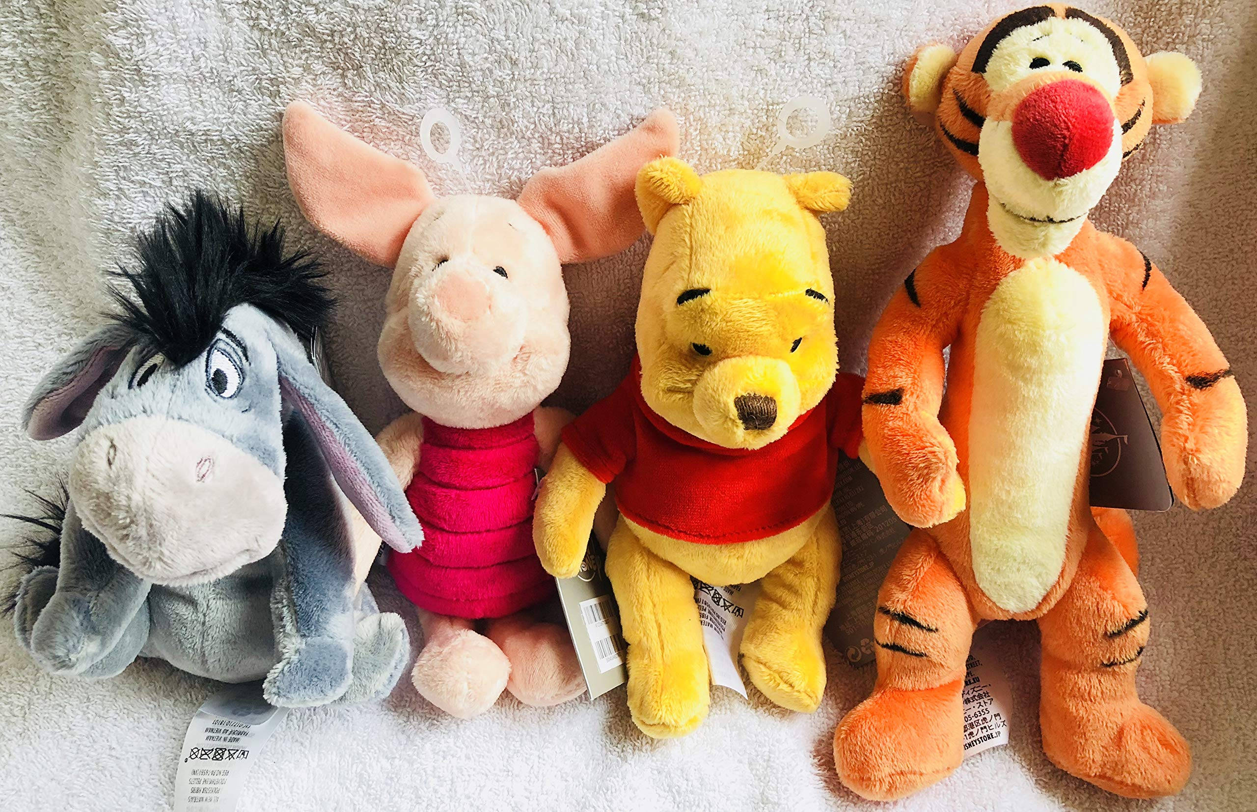 Piglet 桌布 壁紙 — 四個經典小熊維尼毛絨玩具一起坐在柔軟質感的毛巾上，在溫暖舒適的燈光下。