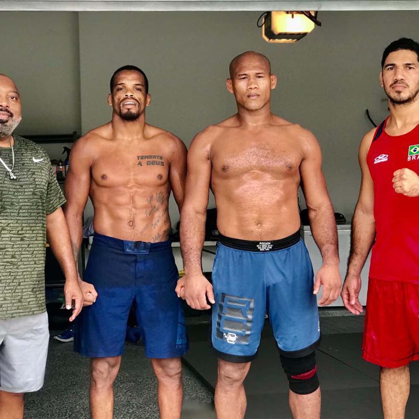 martial arts 桌布 壁紙 — 四個肌肉發達的男人穿著健身服裝自信地站在訓練設施中，其中一人握著另一人的手。