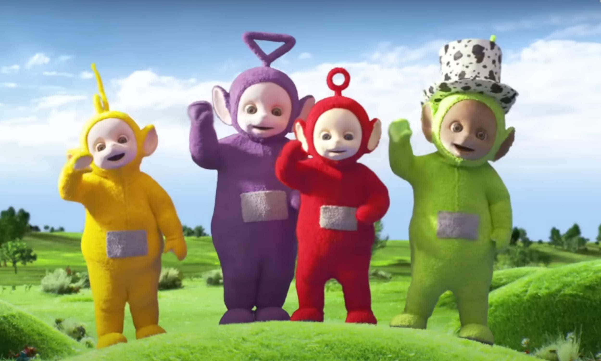 Teletubbies 桌布 壁紙 — 四個色彩繽紛的天線寶寶在藍天白雲下的翠綠山丘上開心地揮手。
