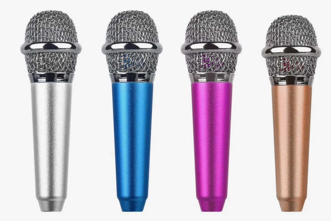 Microphone 桌布 壁紙 — 四個色彩繽紛的手持麥克風，頂部帶有金屬網罩，排列在純白色背景前。