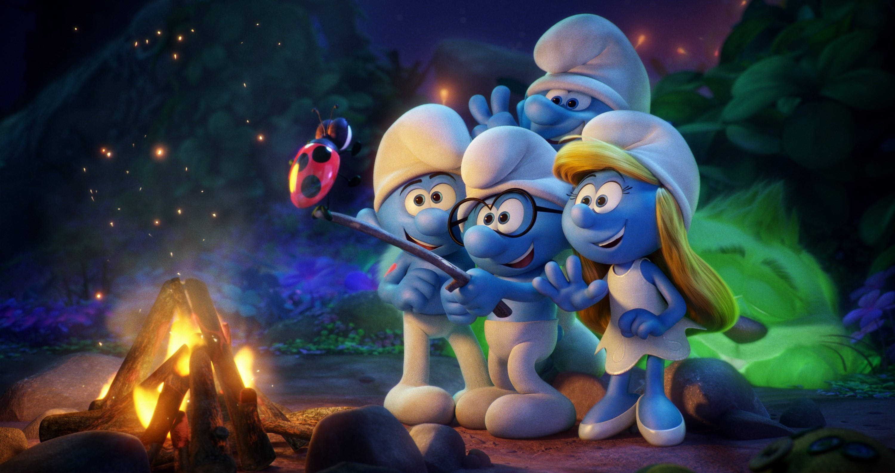 Smurfs 桌布 壁紙 — 四個藍色小精靈夜晚圍著營火，棍子上有隻瓢蟲，在魔法森林中發光。