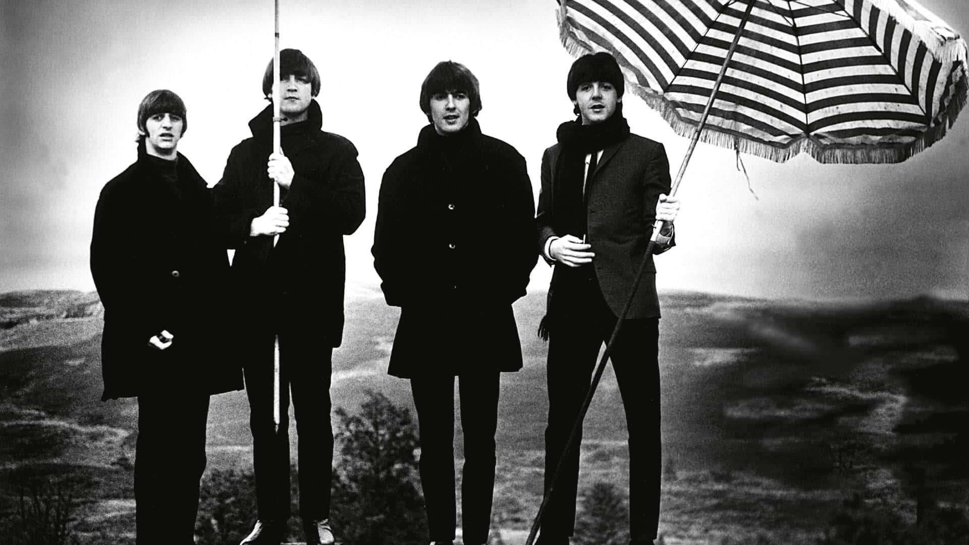 the beatles 桌布 壁紙 — 四個身穿深色大衣的男人站在朦朧的風景前，其中一人高舉一把條紋雨傘，構成充滿氛圍感的黑白肖像。