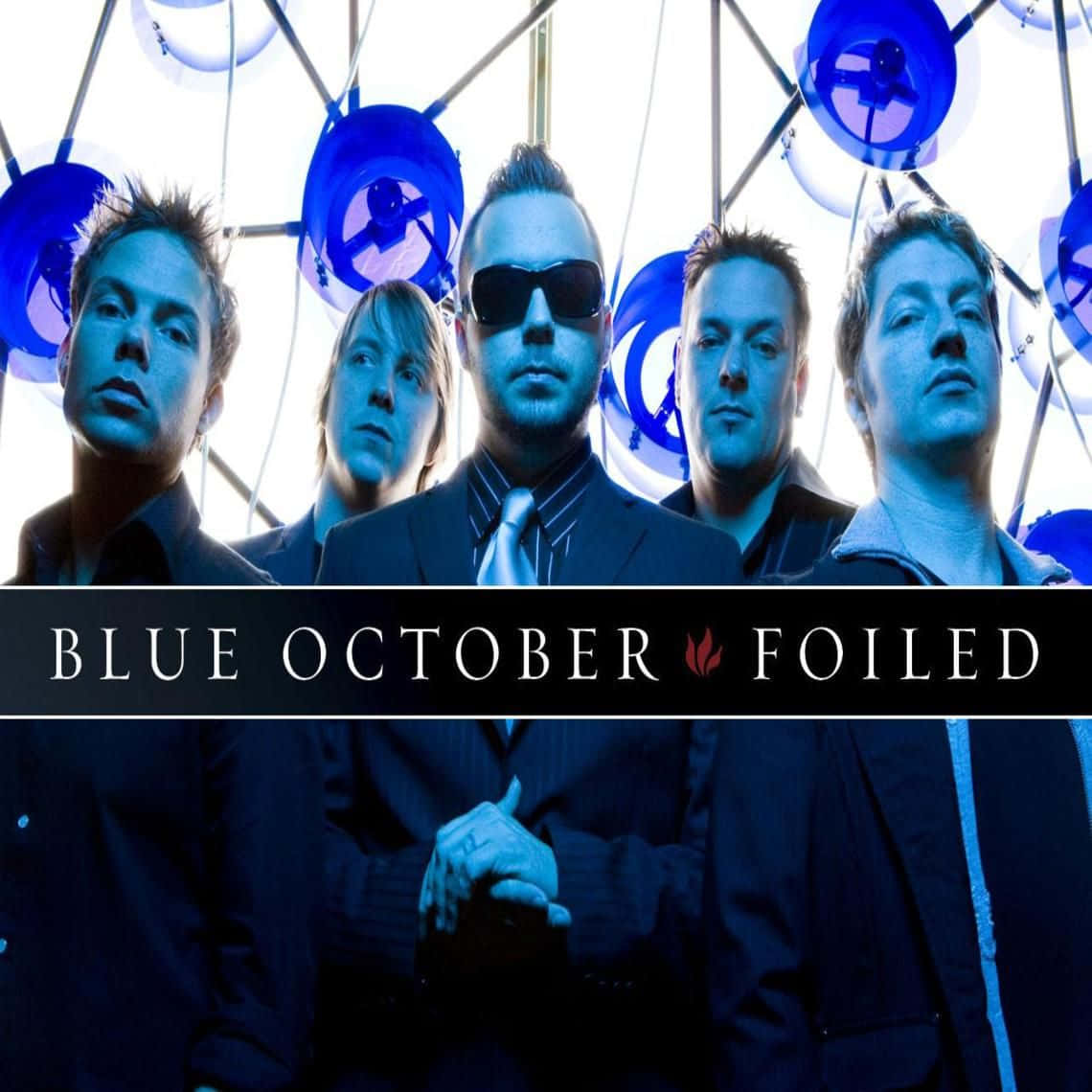 Blue October 桌布 壁紙 — 四個身穿西裝的男人在藍色燈光的幾何圓頂下，帶有圓形風扇，凝視著。