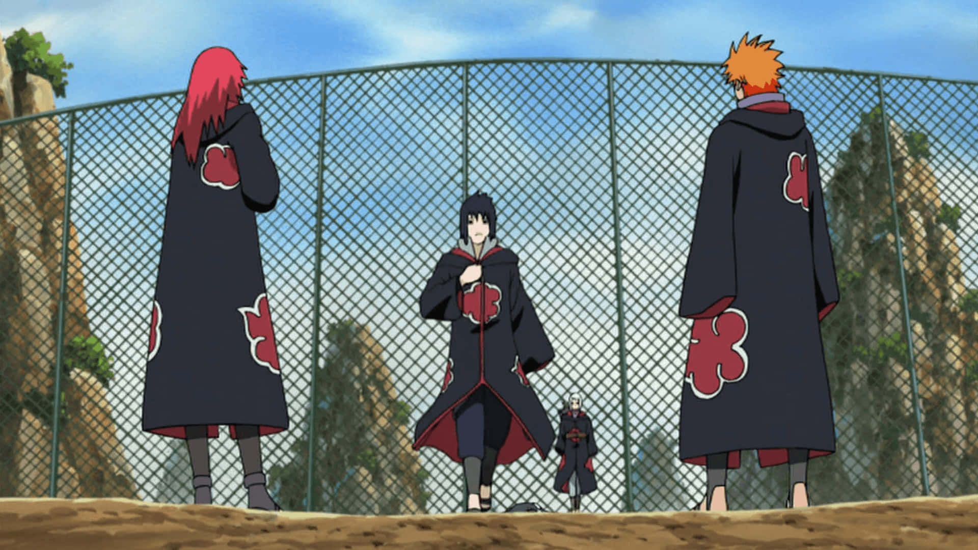 Team Taka Naruto 桌布 壁紙 — 四個身穿黑色斗篷、帶有紅色雲朵圖案的動漫角色，站在一個岩石戶外環境的鐵絲網圍欄後面。