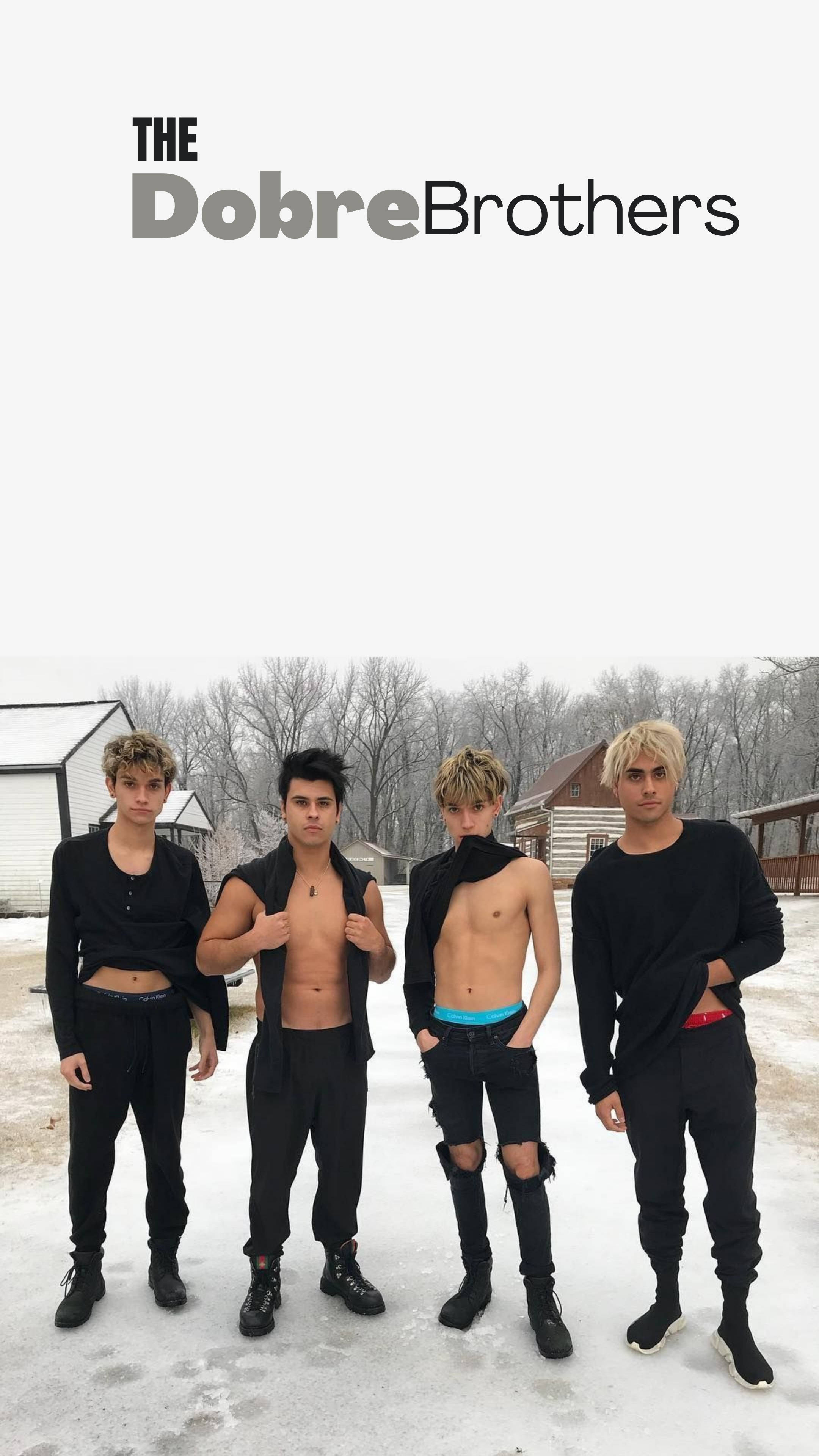 Dobre 桌布 壁紙 — 四個身穿黑色服裝的年輕男子自信地站在雪地上，背後是光禿禿的樹木和質樸的建築。