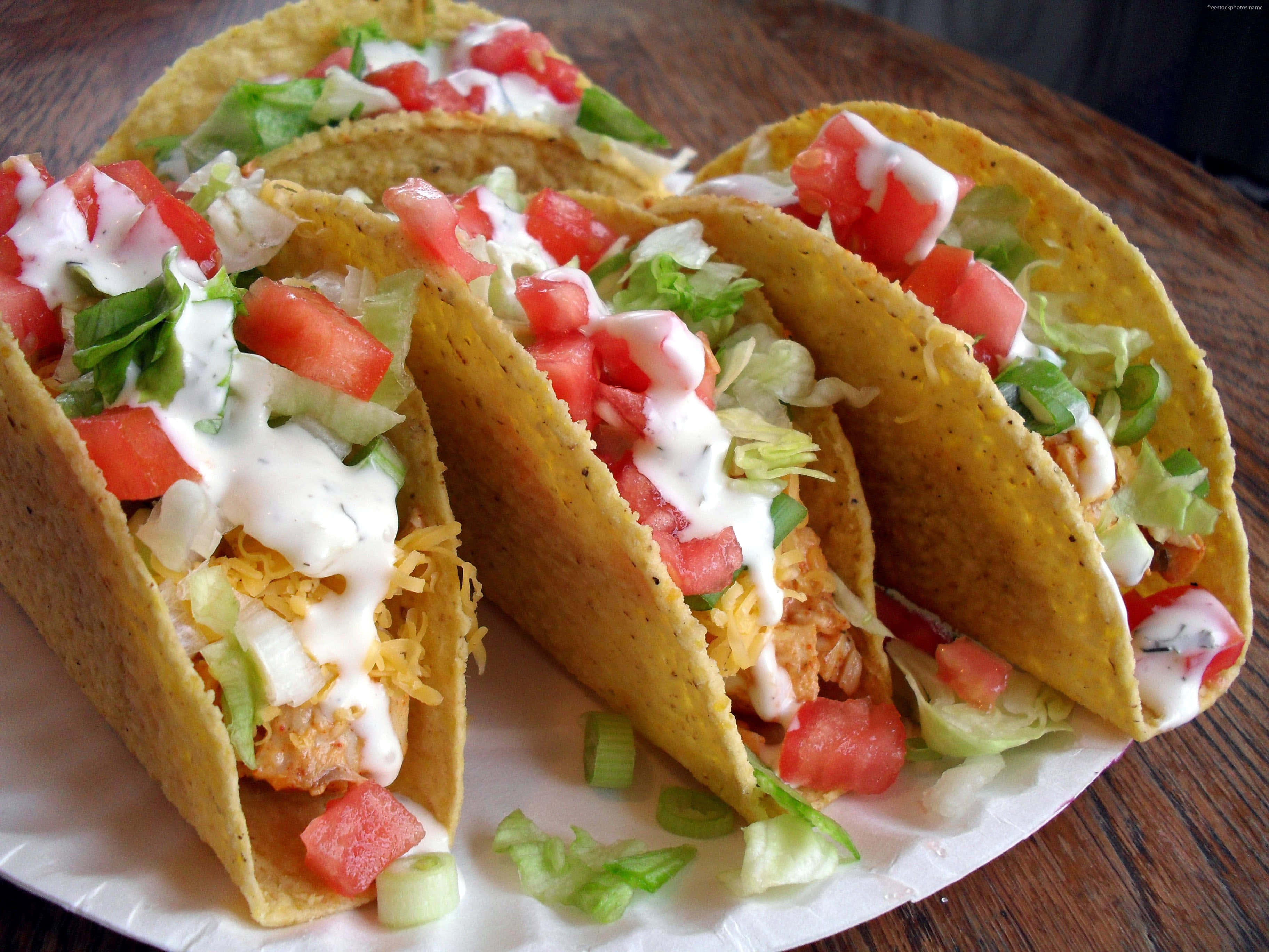 Mexican 桌布 壁紙 — 四個酥脆的玉米餅，裡面裝滿了雞絲、起司、番茄丁、生菜和奶油醬，放在紙盤上，令人垂涎。