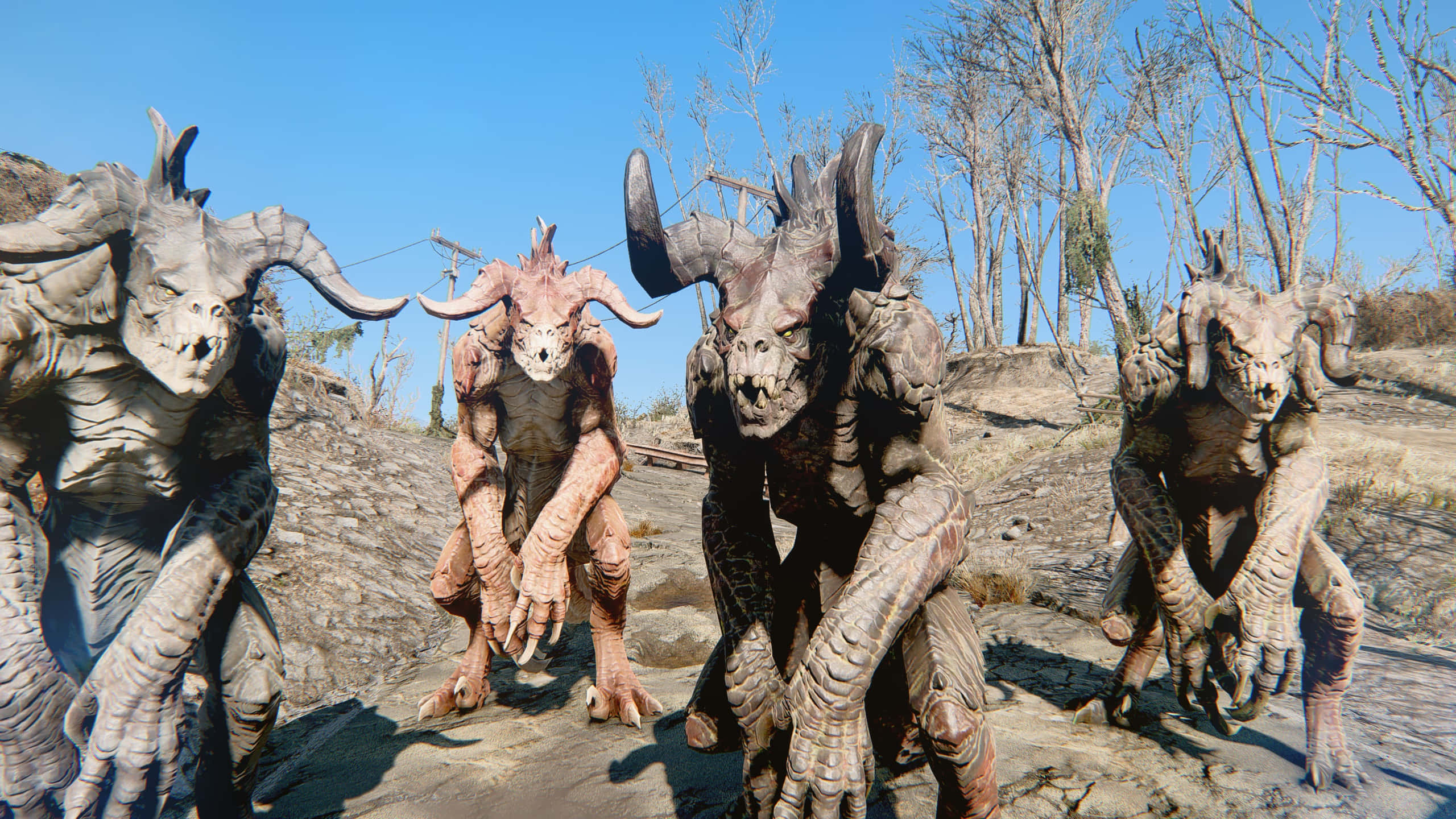 Deathclaw 桌布 壁紙 — 四個長有角、皮膚粗糙的怪獸，在晴朗藍天下的一片貧瘠荒地中威脅性地蹲伏著。