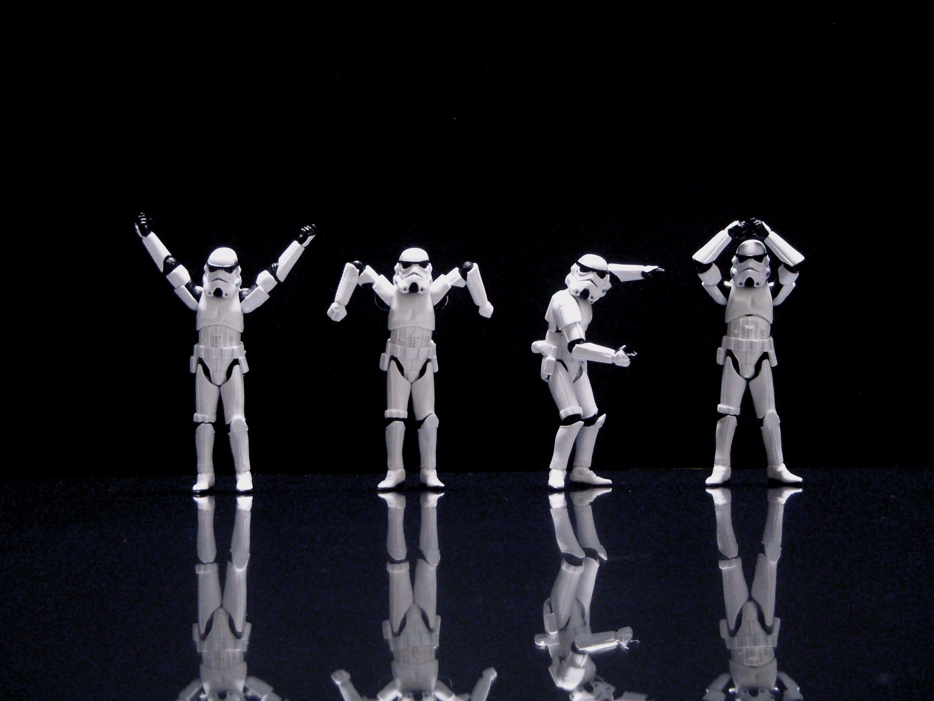 Funny Star Wars 桌布 壁紙 — 四個風暴兵人偶在深色背景下的反光黑色表面上擺出俏皮的姿勢。