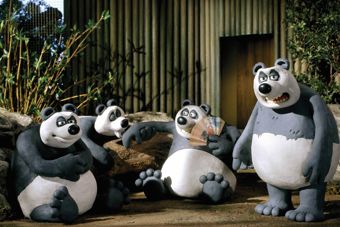 動物 桌布 壁紙 — 四個黏土動畫熊貓在動物園圍欄內坐著和站著，圍欄有竹子和波紋牆。