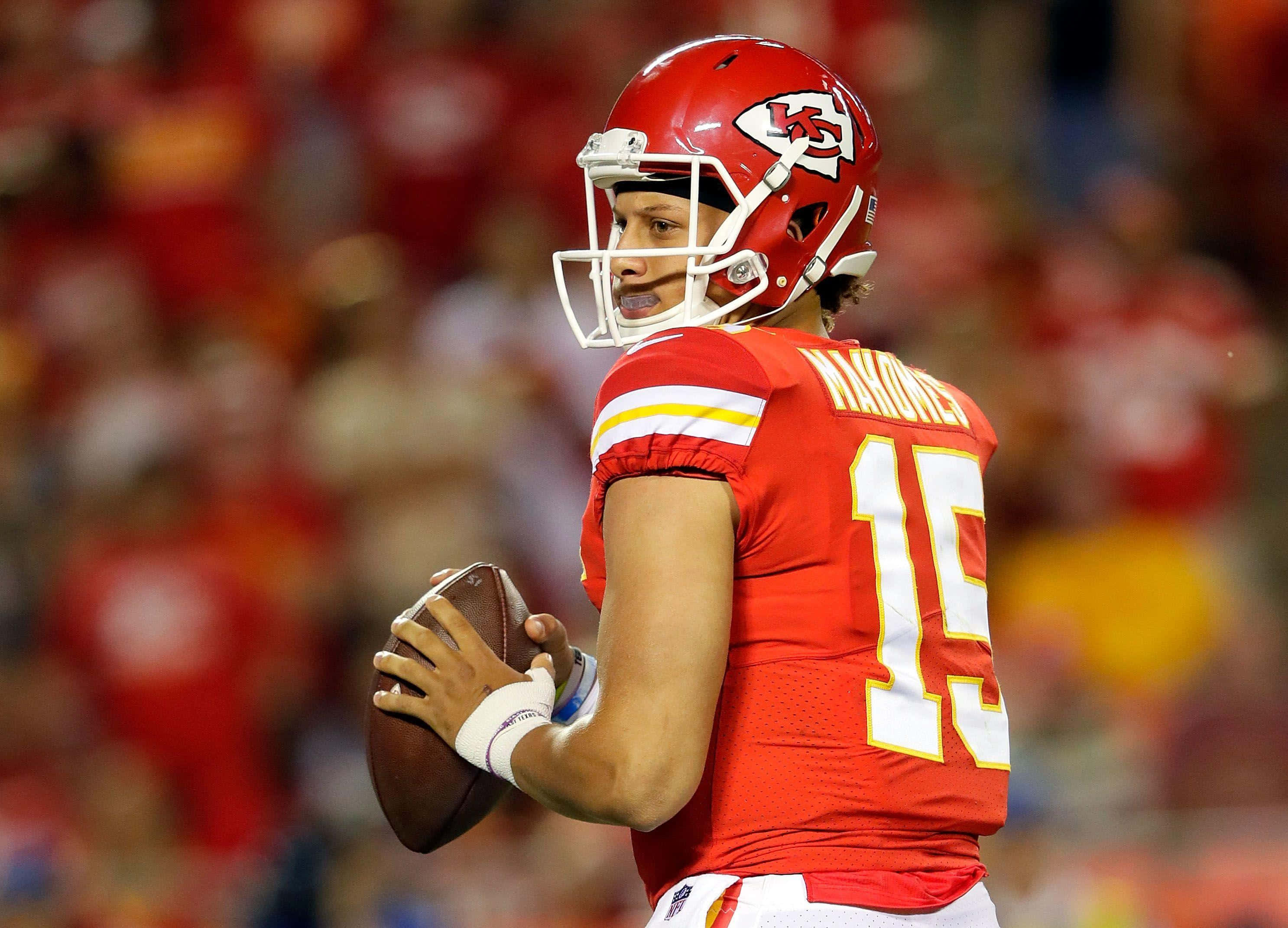 桌布 壁紙 — 四分衛派翠克·馬霍姆斯身穿紅色酋長隊15號球衣，在球場燈光下持球進行比賽。