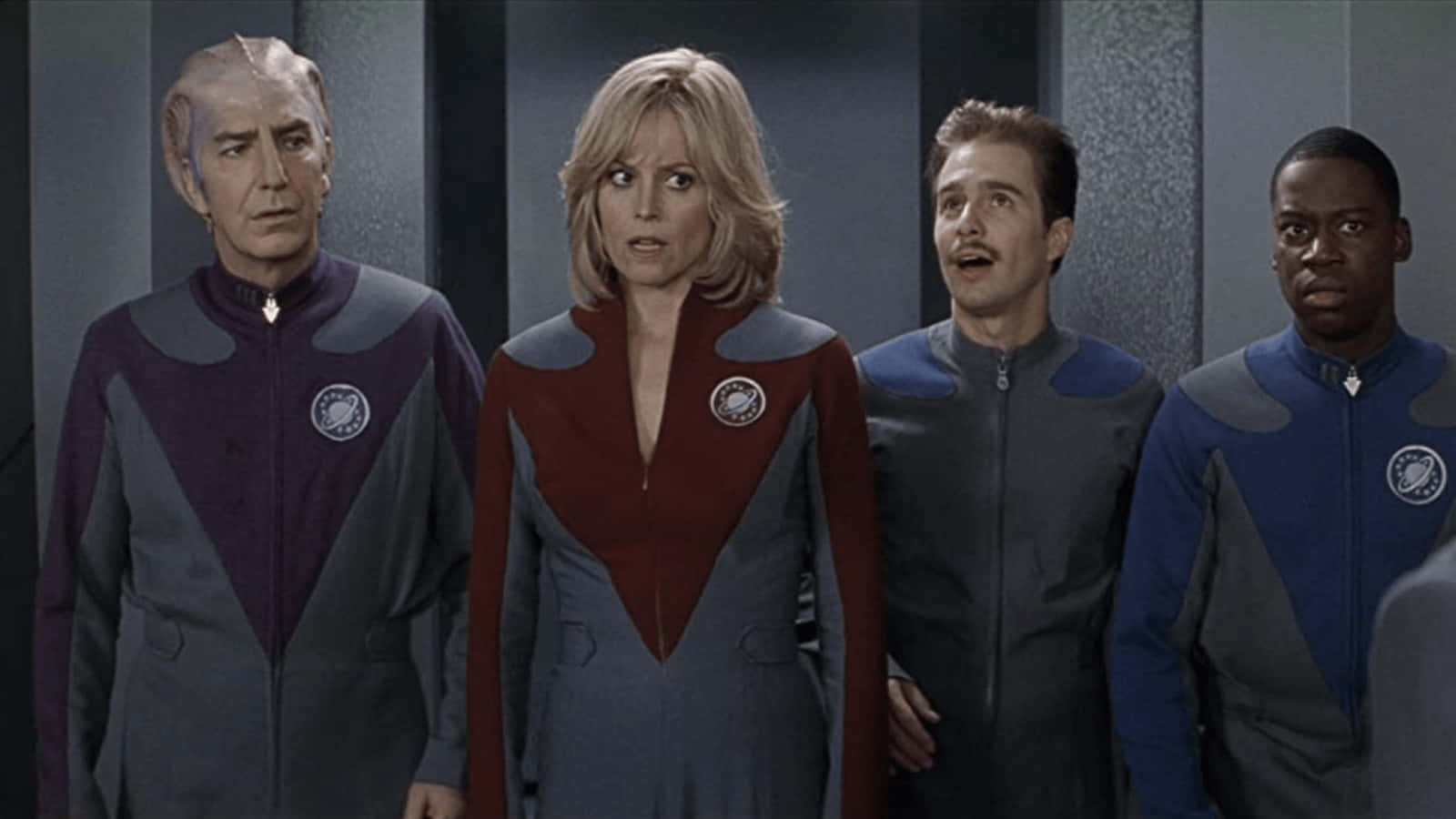 Galaxy Quest 桌布 壁紙 — 四名穿著未來風格制服的船員站在燈光昏暗的太空船走廊，表情震驚。