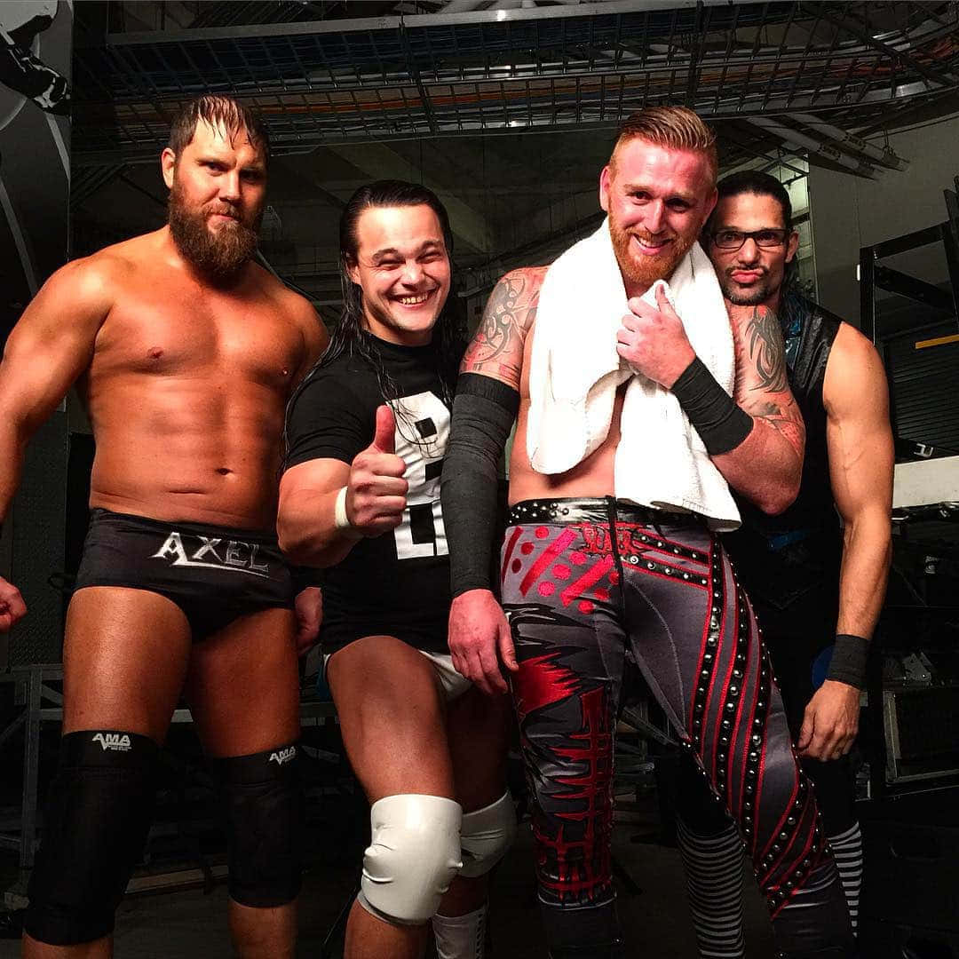 WWE 桌布 壁紙 — 四名肌肉發達的摔角手穿著擂台裝備，在後台自信地擺姿勢，面帶微笑並豎起大拇指。