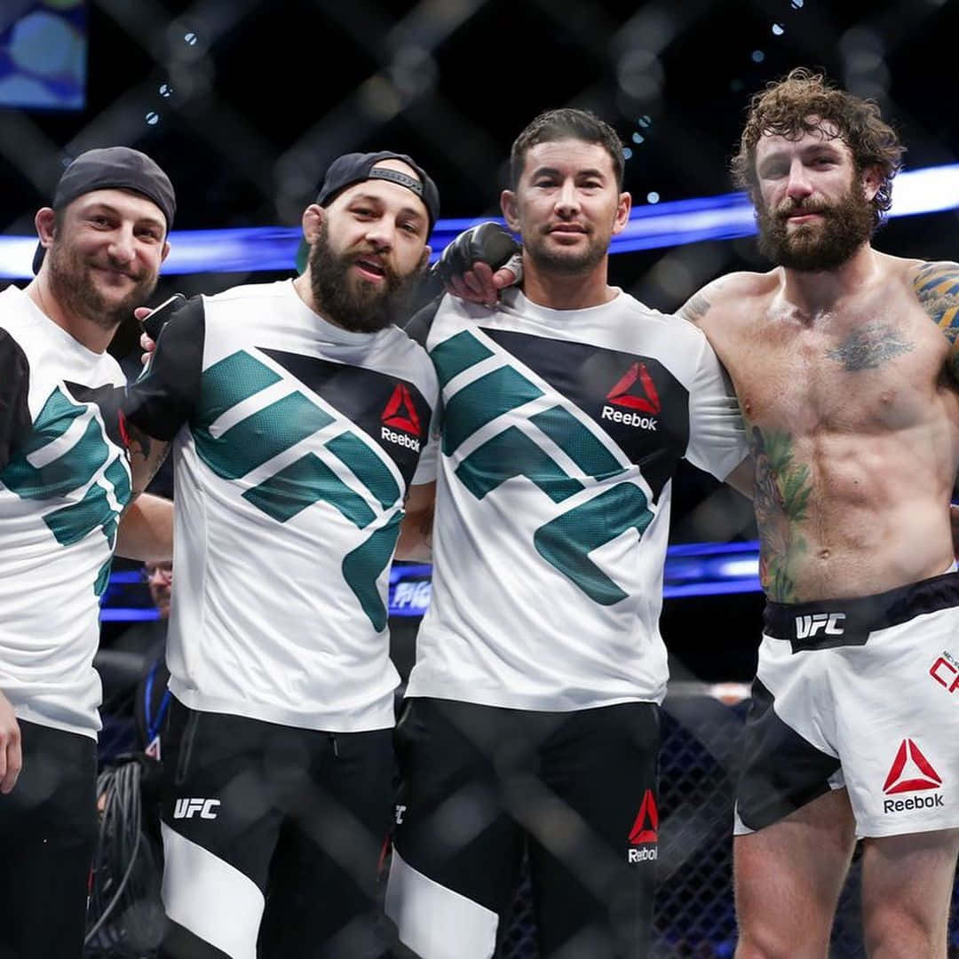 UFC 桌布 壁紙 — 四名身穿Reebok裝備的男性MMA拳手在UFC八角籠內以明亮的藍色燈光一起擺姿勢。