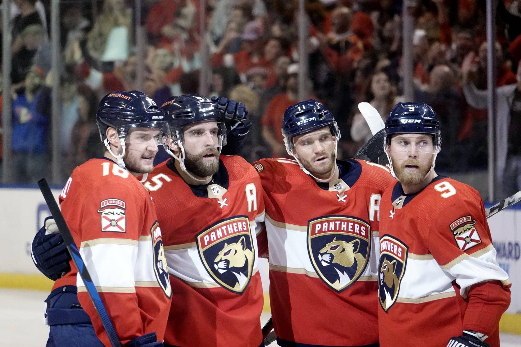 hockey 桌布 壁紙 — 四名身穿紅色球衣的佛羅里達美洲豹冰球球員在比賽中於冰上一起慶祝，背景有球迷。