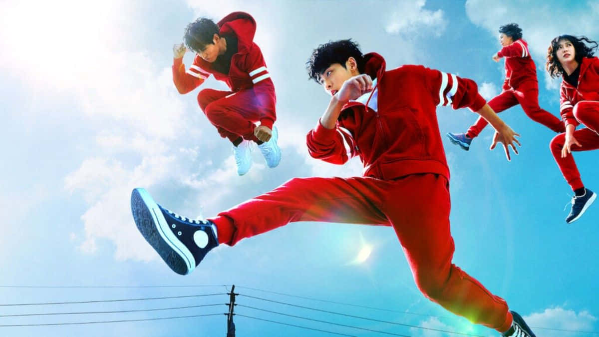 Parkour 桌布 壁紙 — 四名身穿紅色運動服的青少年在明亮的藍天、蓬鬆的雲朵和下方的電線襯托下動態跳躍。