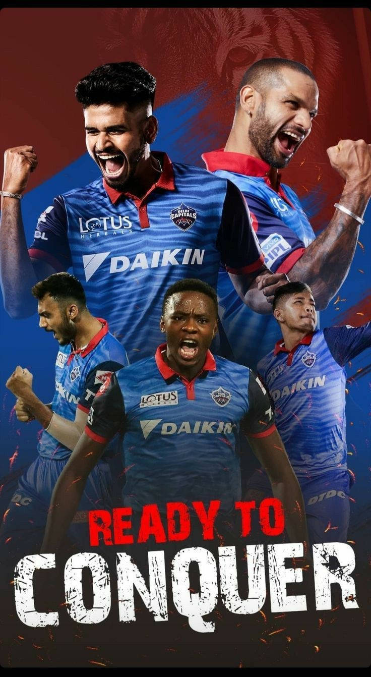 Delhi Capitals 桌布 壁紙 — 四名身穿藍色球衣的板球運動員在火花四濺的熾熱紅藍背景下發出勝利的咆哮。
