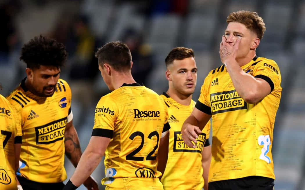 Brumbies 桌布 壁紙 — 四名身穿黃色球衣的橄欖球運動員在夜間比賽中，於球場燈光下激烈反應。