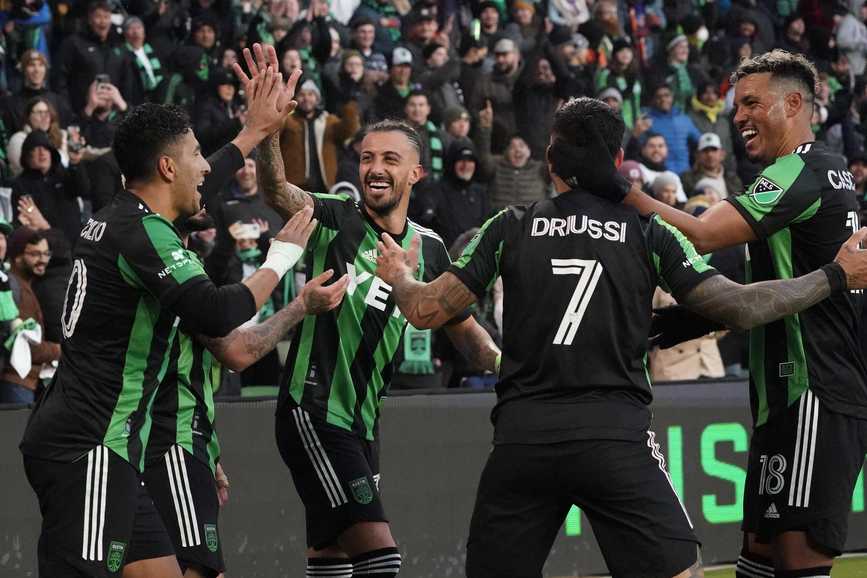 Austin Fc 桌布 壁紙 — 四名身穿黑綠條紋球衣的足球員在球場上擊掌慶祝進球，表情歡樂。