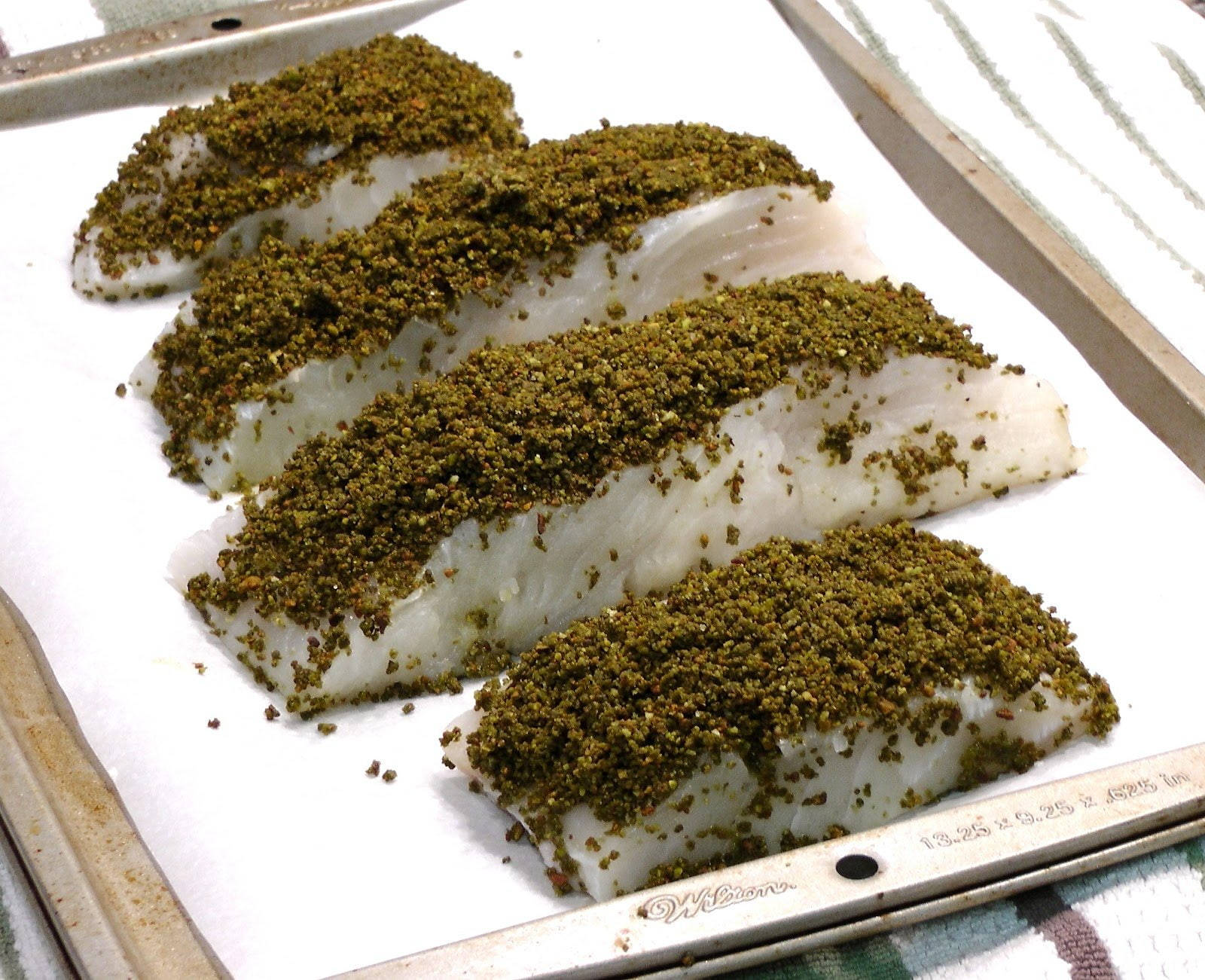 魚 桌布 壁紙 — 四塊生魚片裹上綠色香草外皮，放在金屬烤盤上的烘焙紙上。