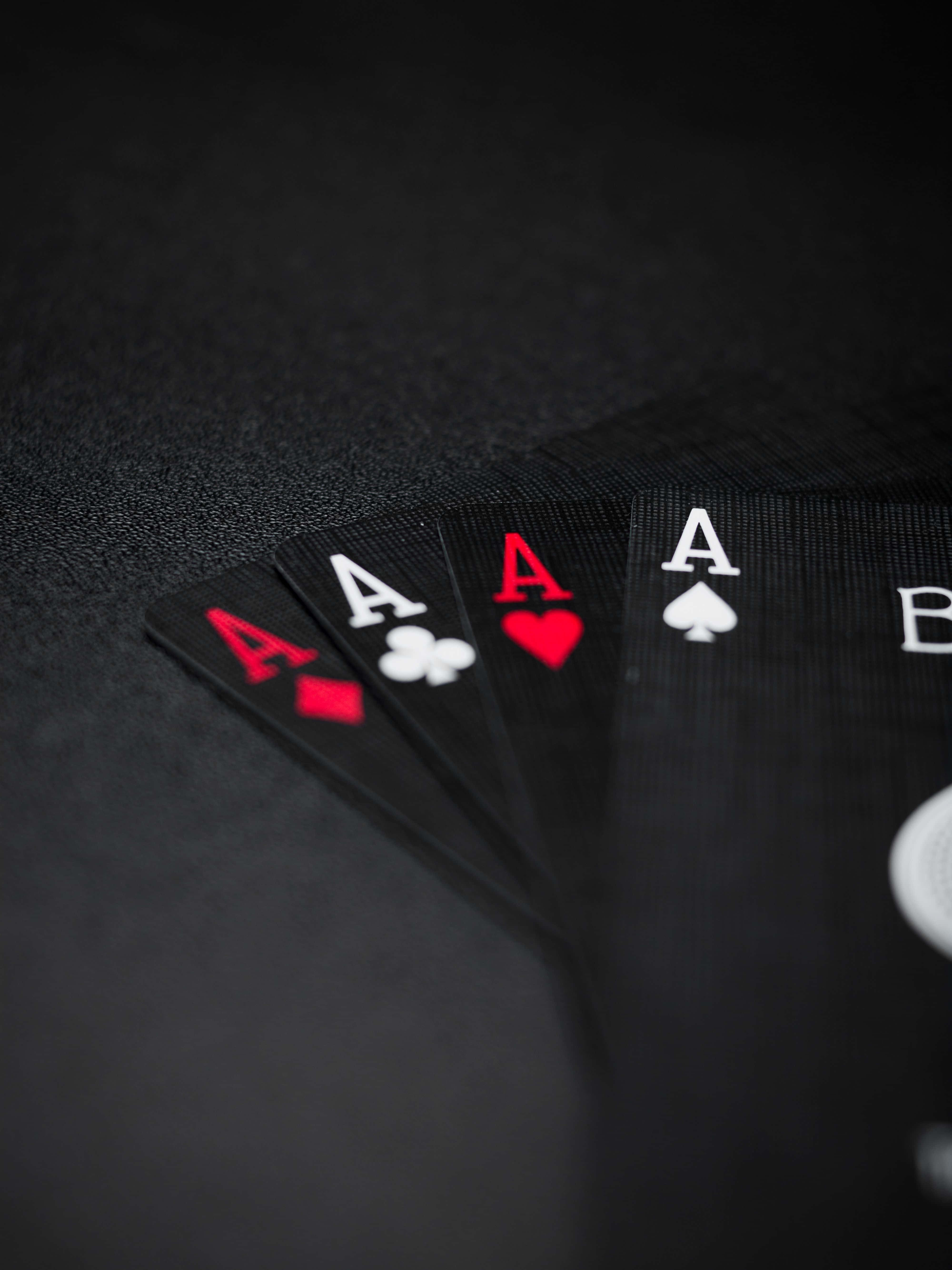 Poker 桌布 壁紙 — 四張Ace撲克牌以扇形展開在深色紋理表面上，景深較淺。