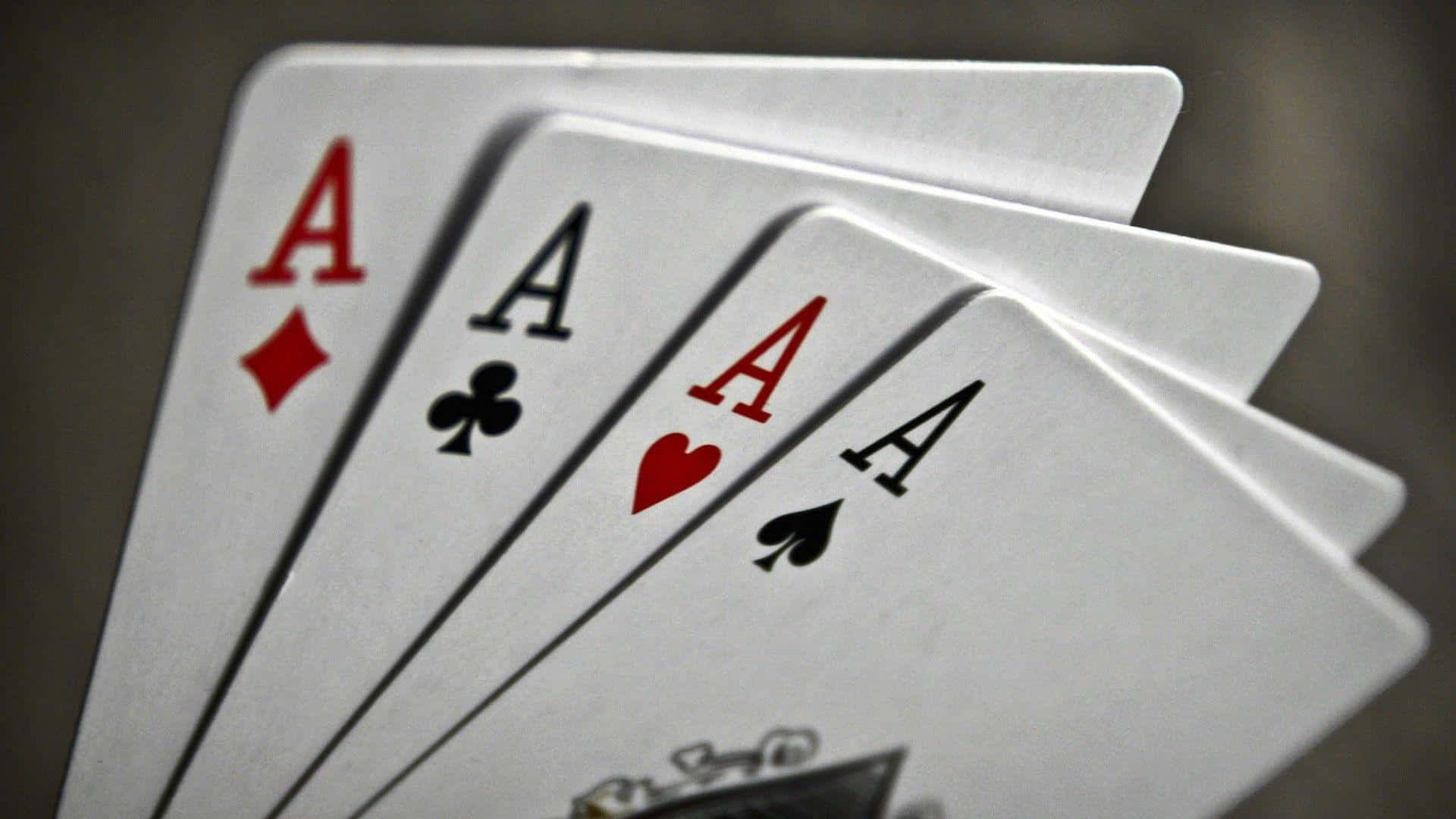 Playing Cards 桌布 壁紙 — 四張撲克牌Ace以扇形展開，清晰對焦在模糊的深色背景上。