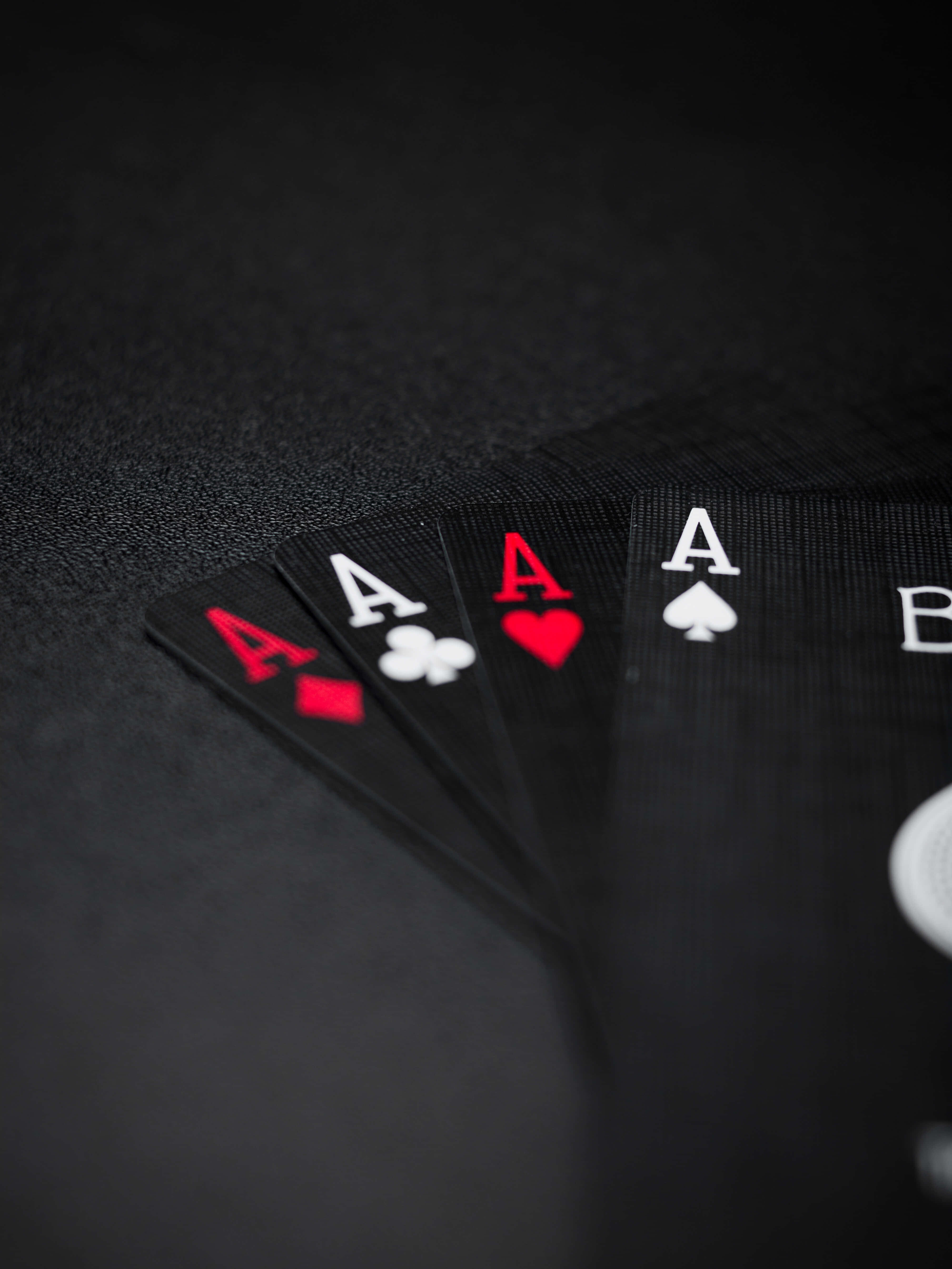 Card Games 桌布 壁紙 — 四張撲克牌Ace以扇形排列在深色紋理表面上，景深較淺。