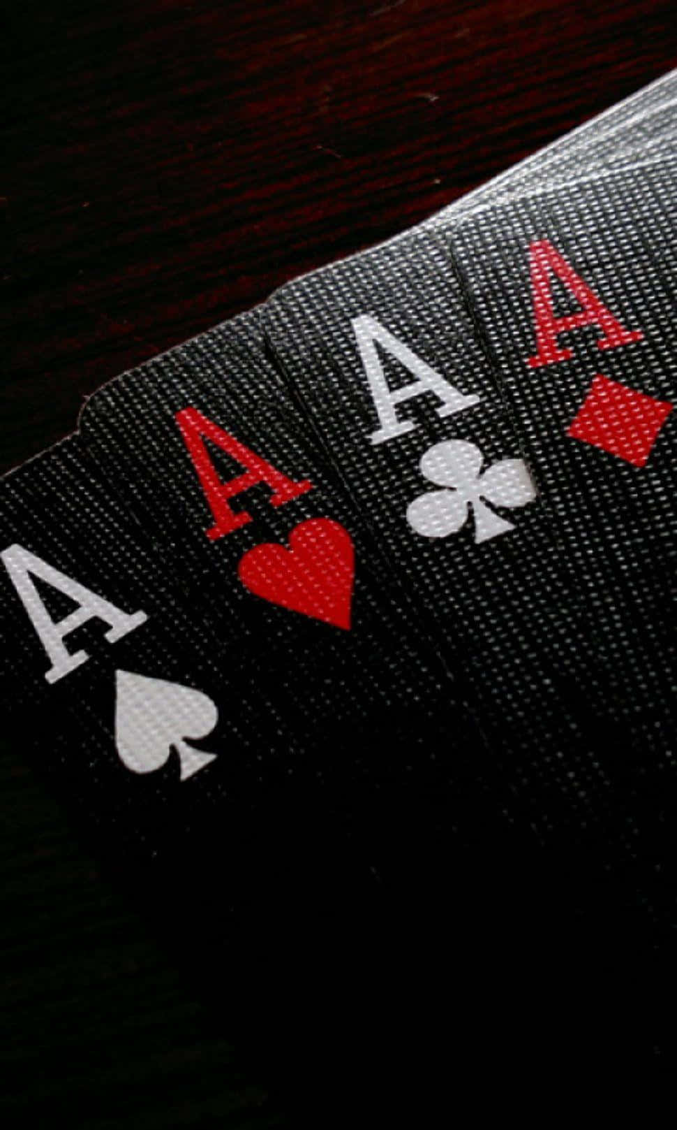 Poker 桌布 壁紙 — 四張撲克牌Ace在深色木質表面上以戲劇性燈光展開。