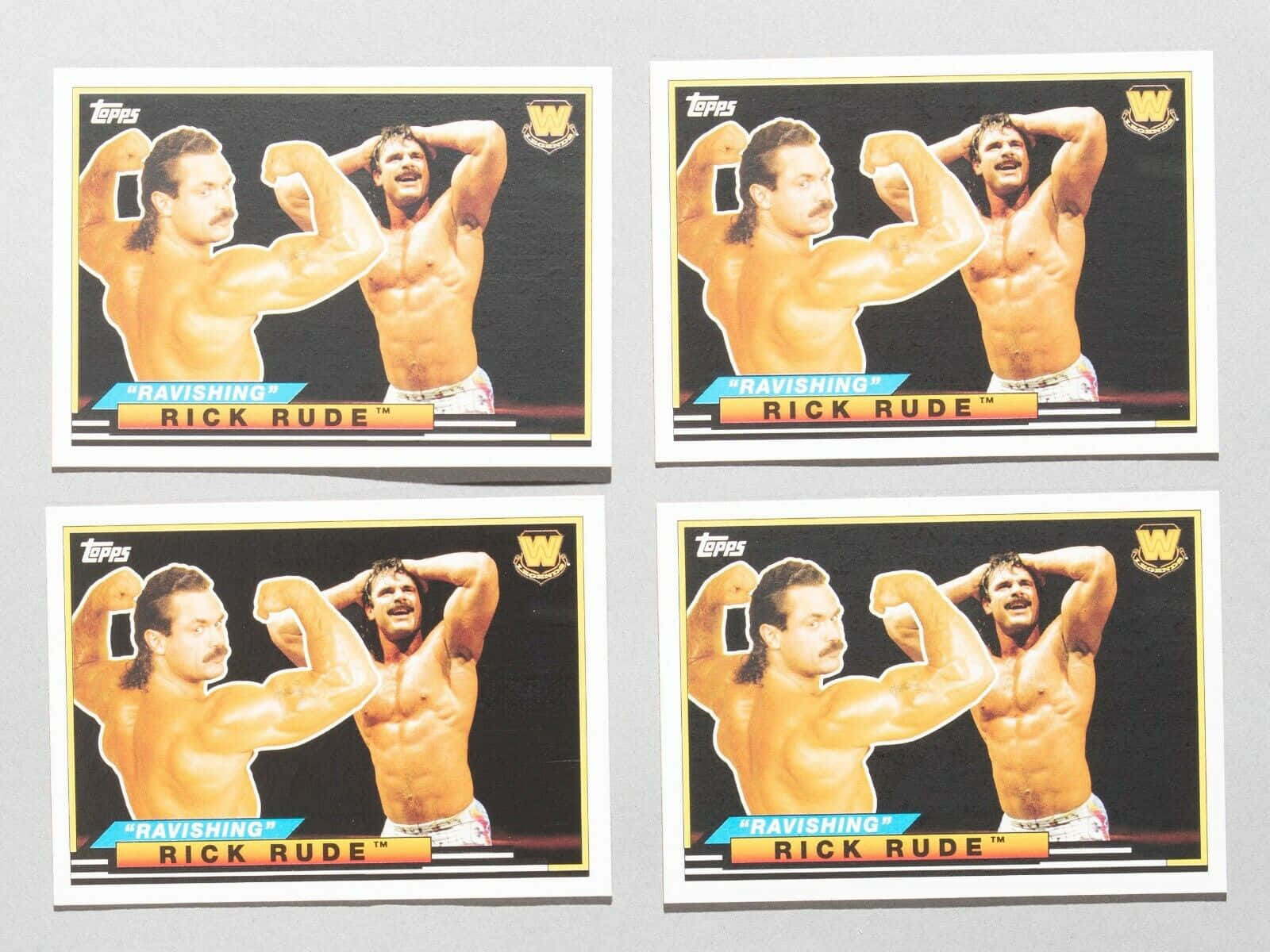 摔角 桌布 壁紙 — 四張相同的復古摔角交易卡，Rick Rude 在黑色背景上擺姿勢，帶有黃色邊框。
