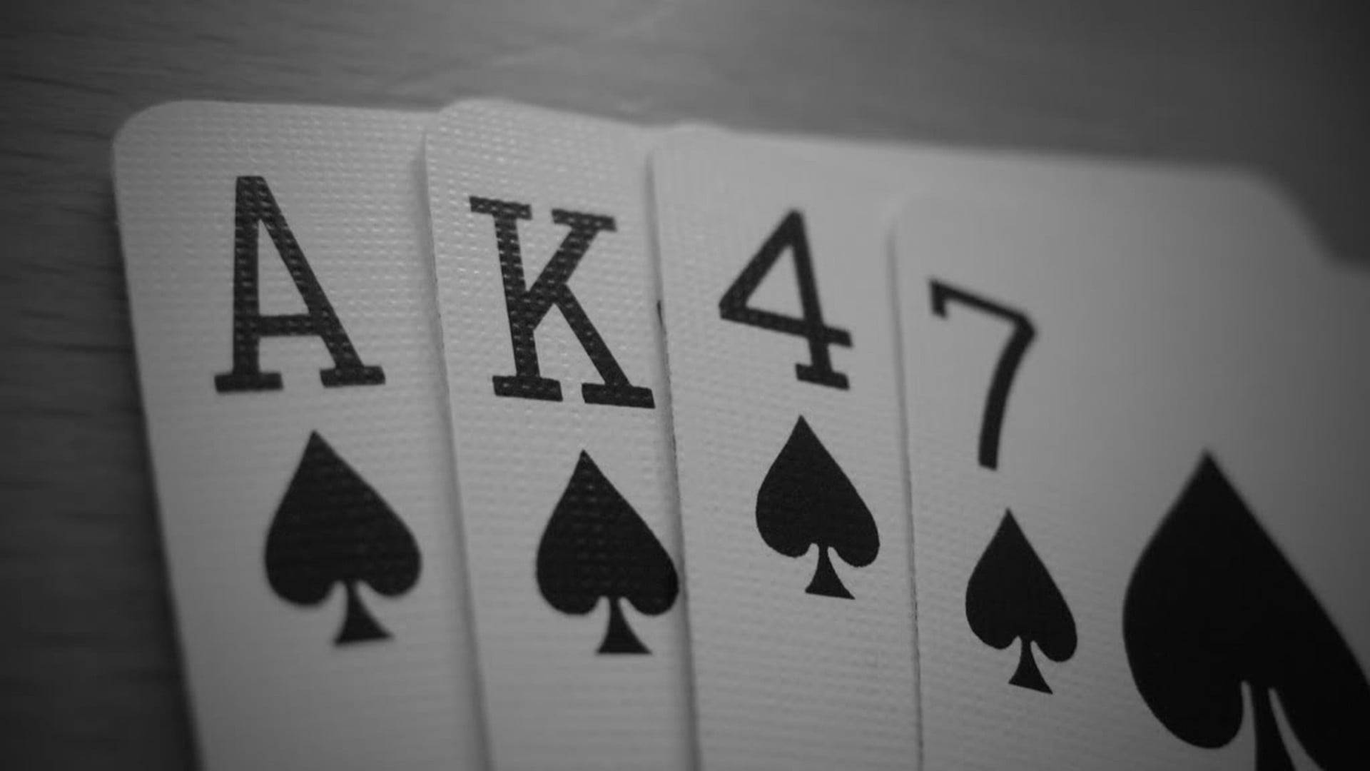 國王 桌布 壁紙 — 四張黑桃撲克牌 Ace King Four Seven 以單色扇形展開在帶紋理的木質表面上。