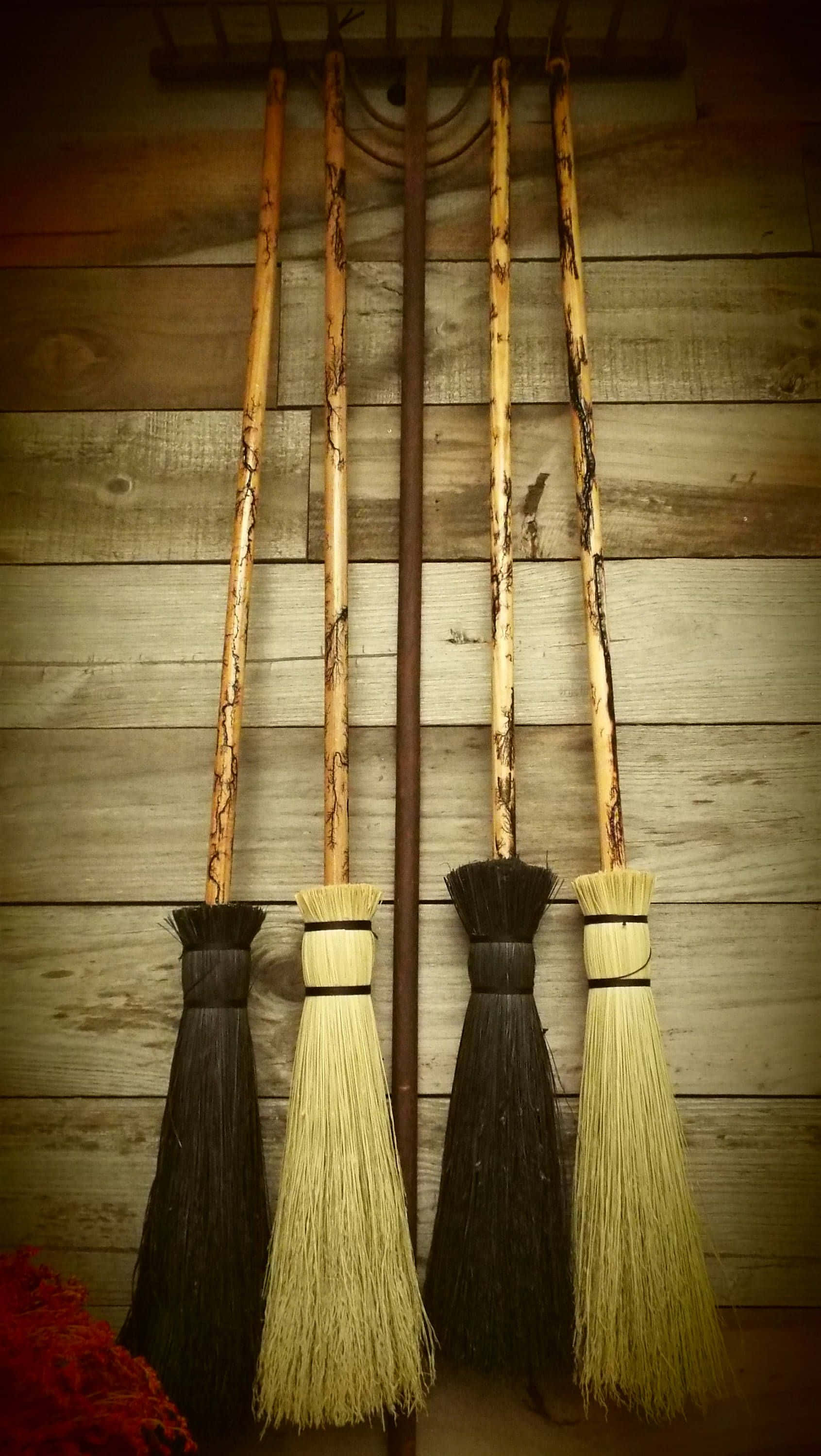 Witches Broom 桌布 壁紙 — 四把帶有天然刷毛的鄉村風格掃帚，掛在溫暖懷舊色調的風化木牆上。