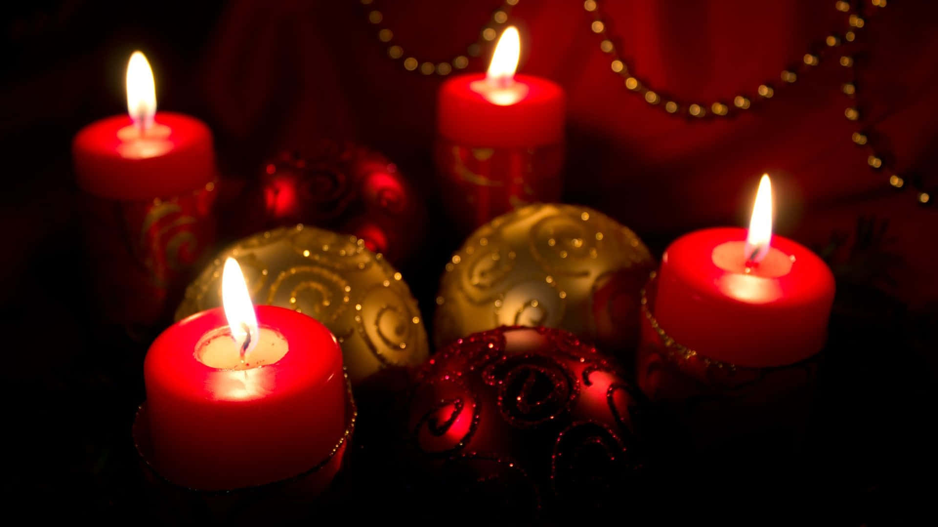 Advent 桌布 壁紙 — 四支發光的紅色蠟燭和閃閃發光的紅金色裝飾品在昏暗的燈光下營造出溫暖的節日氛圍。