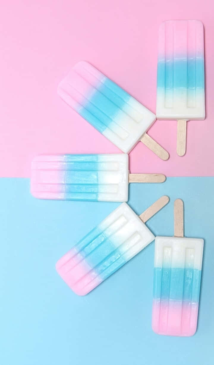 Pastel Blue And Pink 桌布 壁紙 — 四支粉紅、藍、白漩渦紋的粉彩漸變冰棒放在粉紅和藍色分割的背景上。
