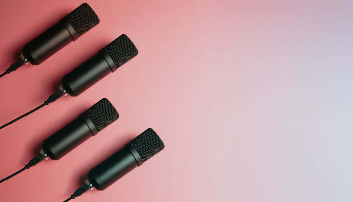 Microphones 桌布 壁紙 — 四支黑色錄音室麥克風以對角線排列在柔和的粉紅色到薰衣草漸變背景上。