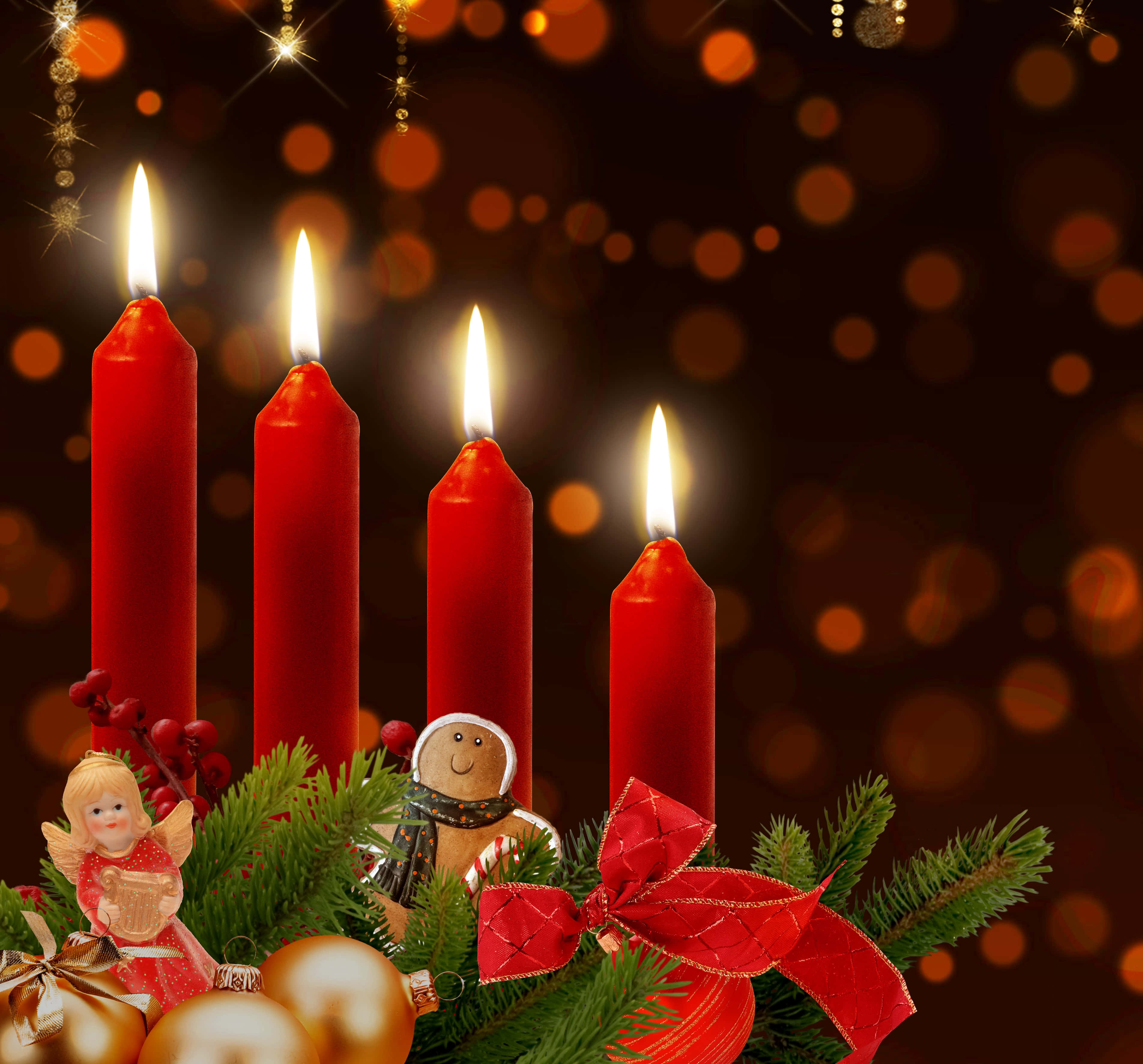 Advent 桌布 壁紙 — 四支點燃的紅色蠟燭在節日松枝、裝飾品和薑餅人旁邊溫暖地發光，背景是閃爍的散景。