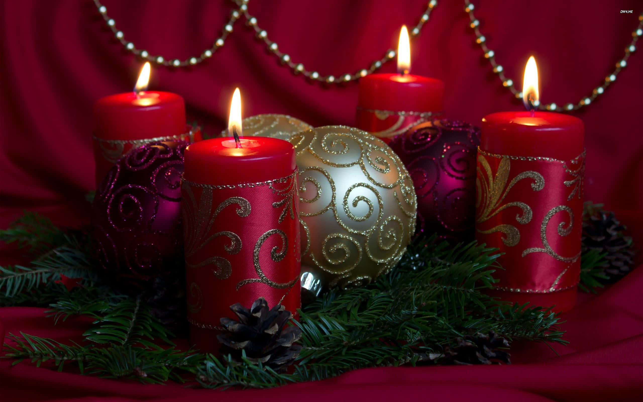 Advent 桌布 壁紙 — 四支點燃的紅色蠟燭帶有金色漩渦，在豐富的紅色布料上，旁邊有金色裝飾品和松果，溫暖地發光。