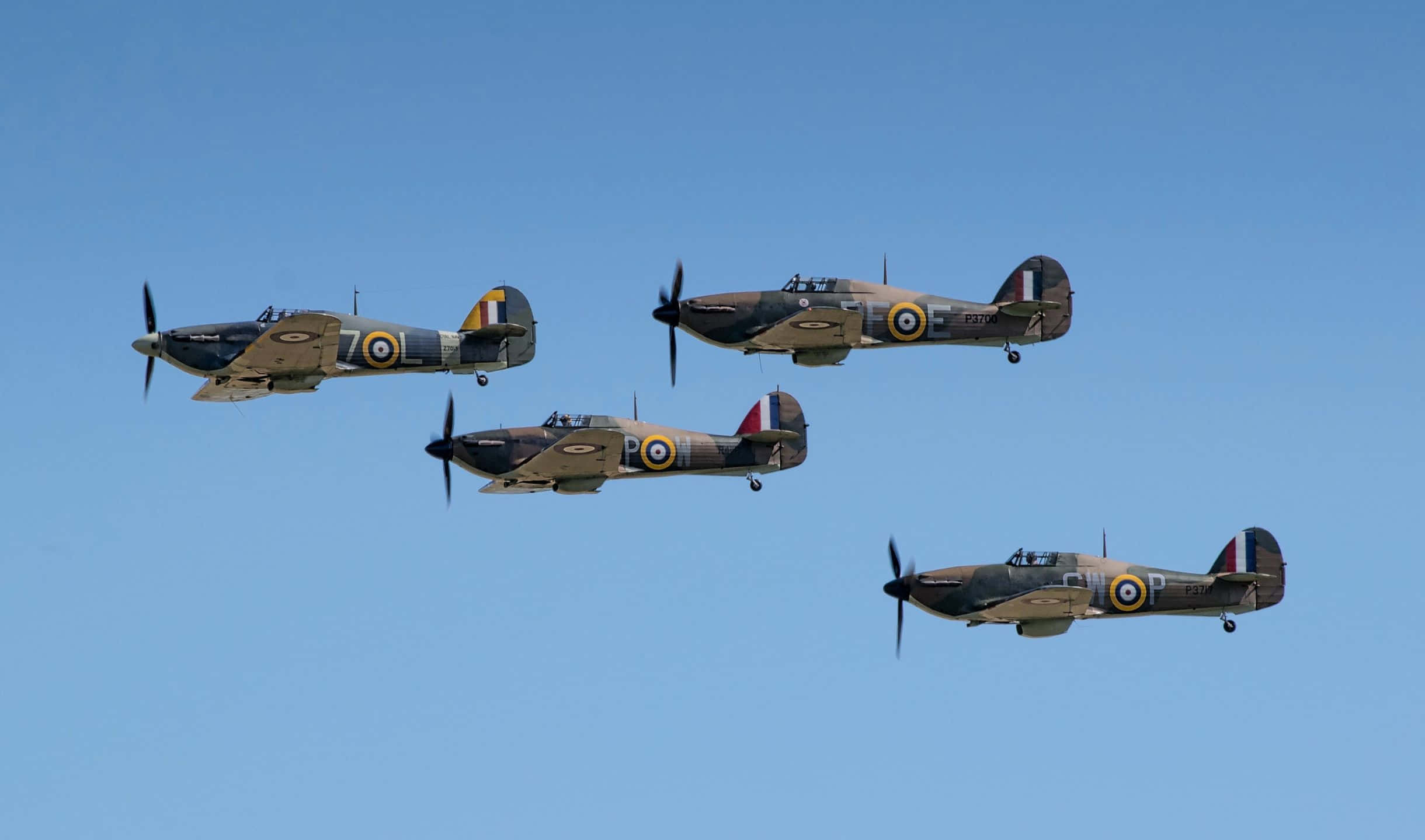 2440x1440 Small Planes 桌布 壁紙 — 四架復古軍用戰鬥機在清澈的藍天下編隊飛行。