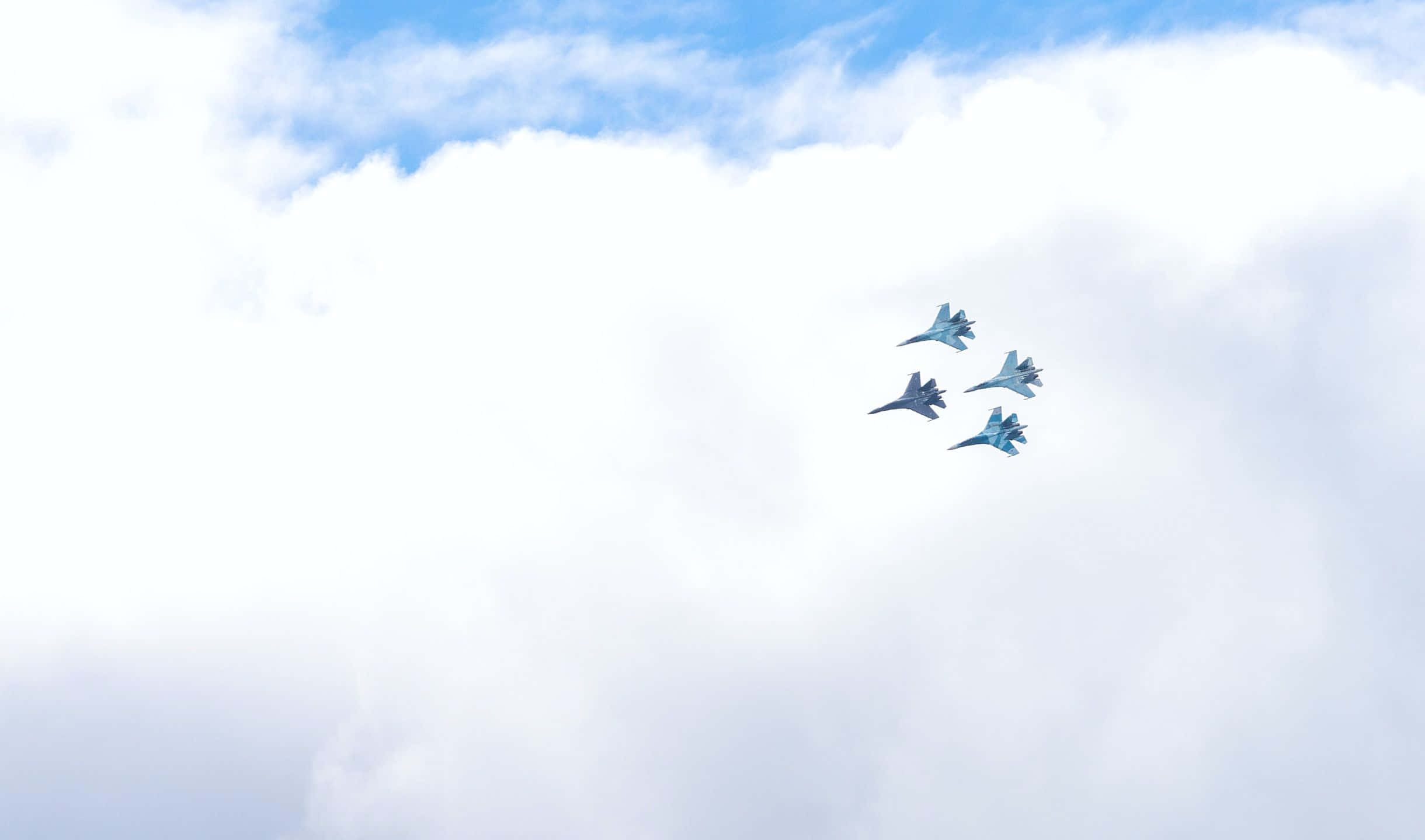 2440x1440 Small Planes 桌布 壁紙 — 四架戰鬥機以緊密編隊翱翔於充滿蓬鬆白雲的明亮天空中。