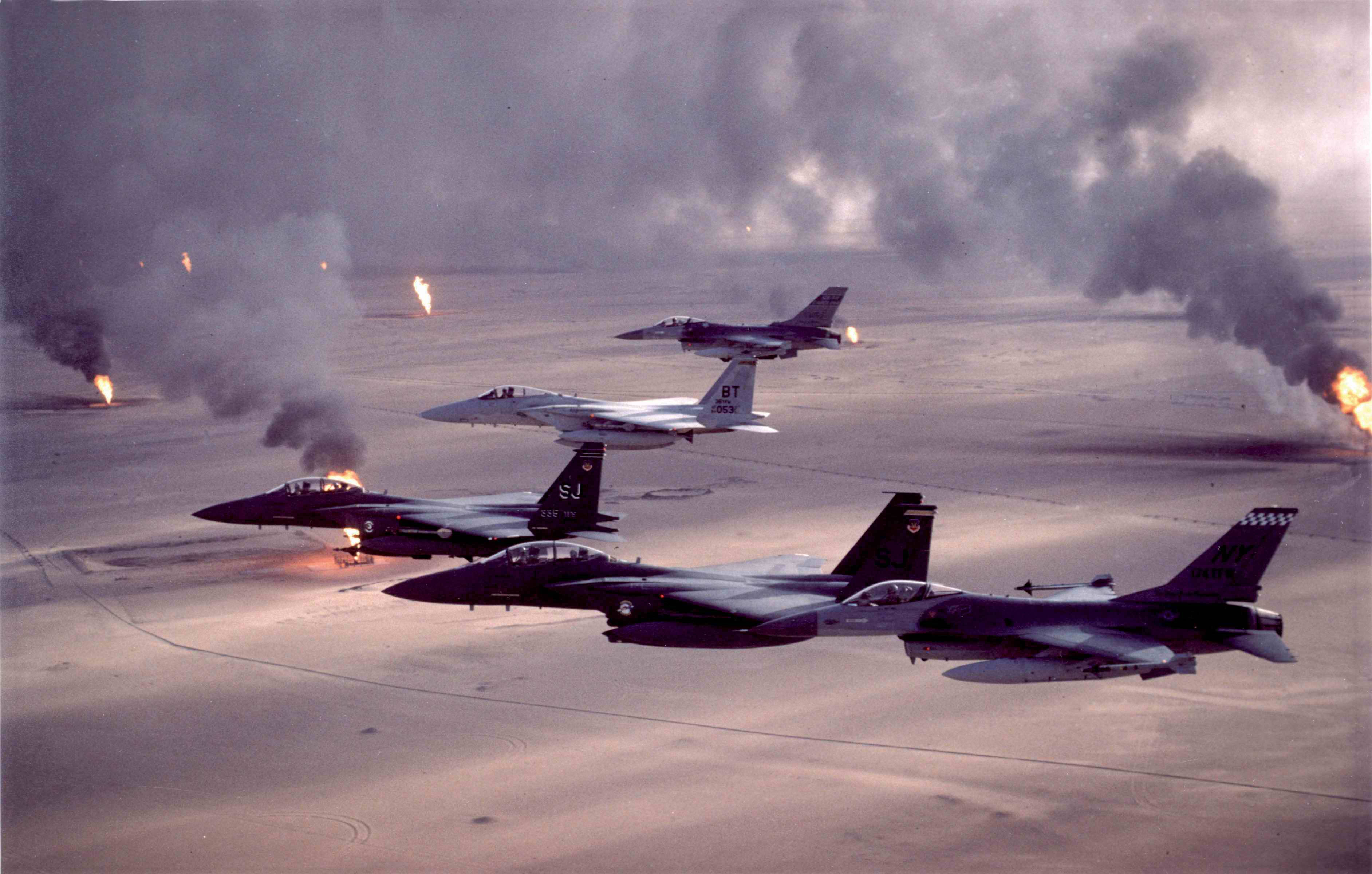 Air Force 桌布 壁紙 — 四架戰鬥機低飛越過沙漠戰場，背後油井燃燒，黑煙升騰。
