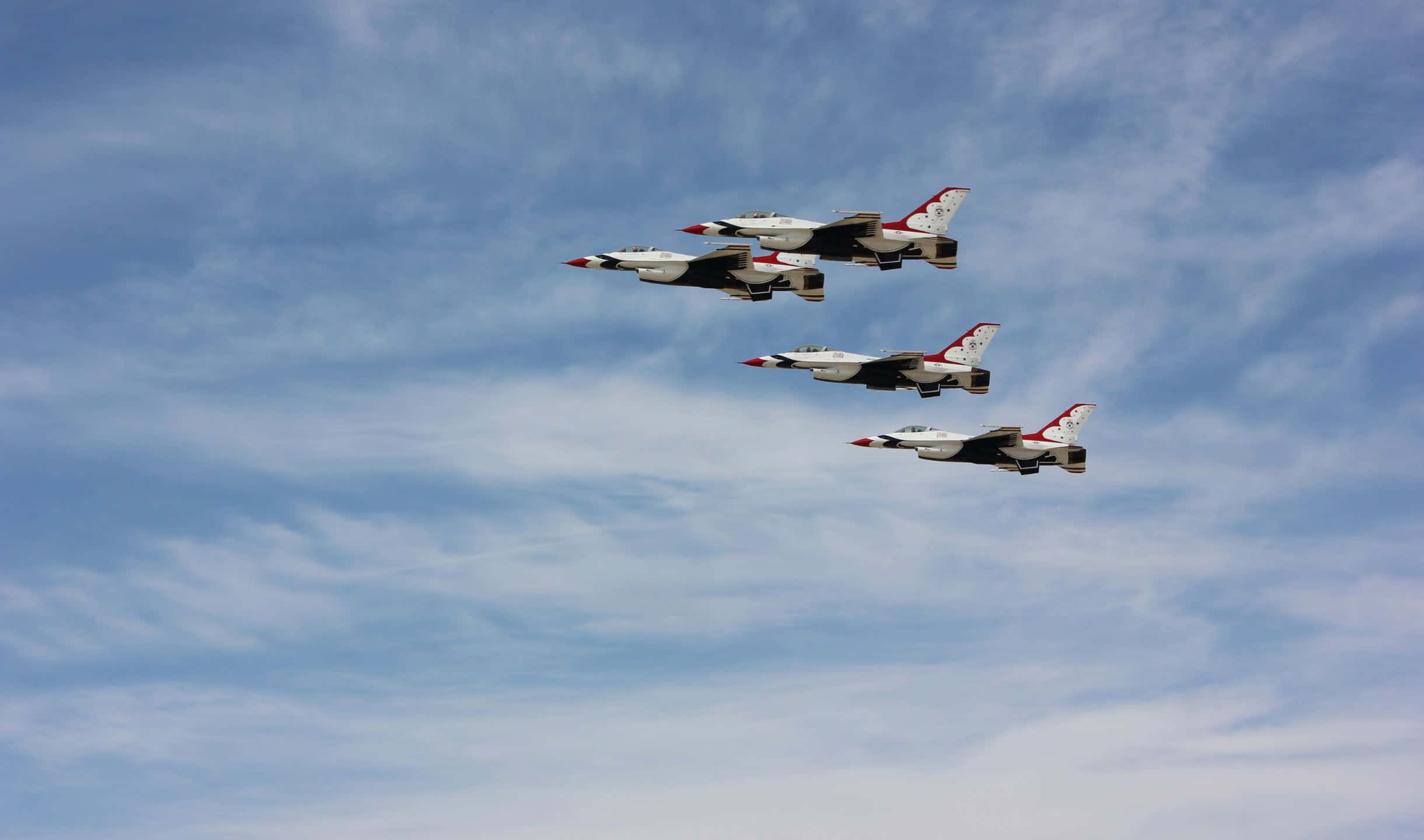 2440x1440 Small Planes 桌布 壁紙 — 四架戰鬥機在廣闊的藍天中緊密編隊翱翔，天空點綴著縷縷白雲。