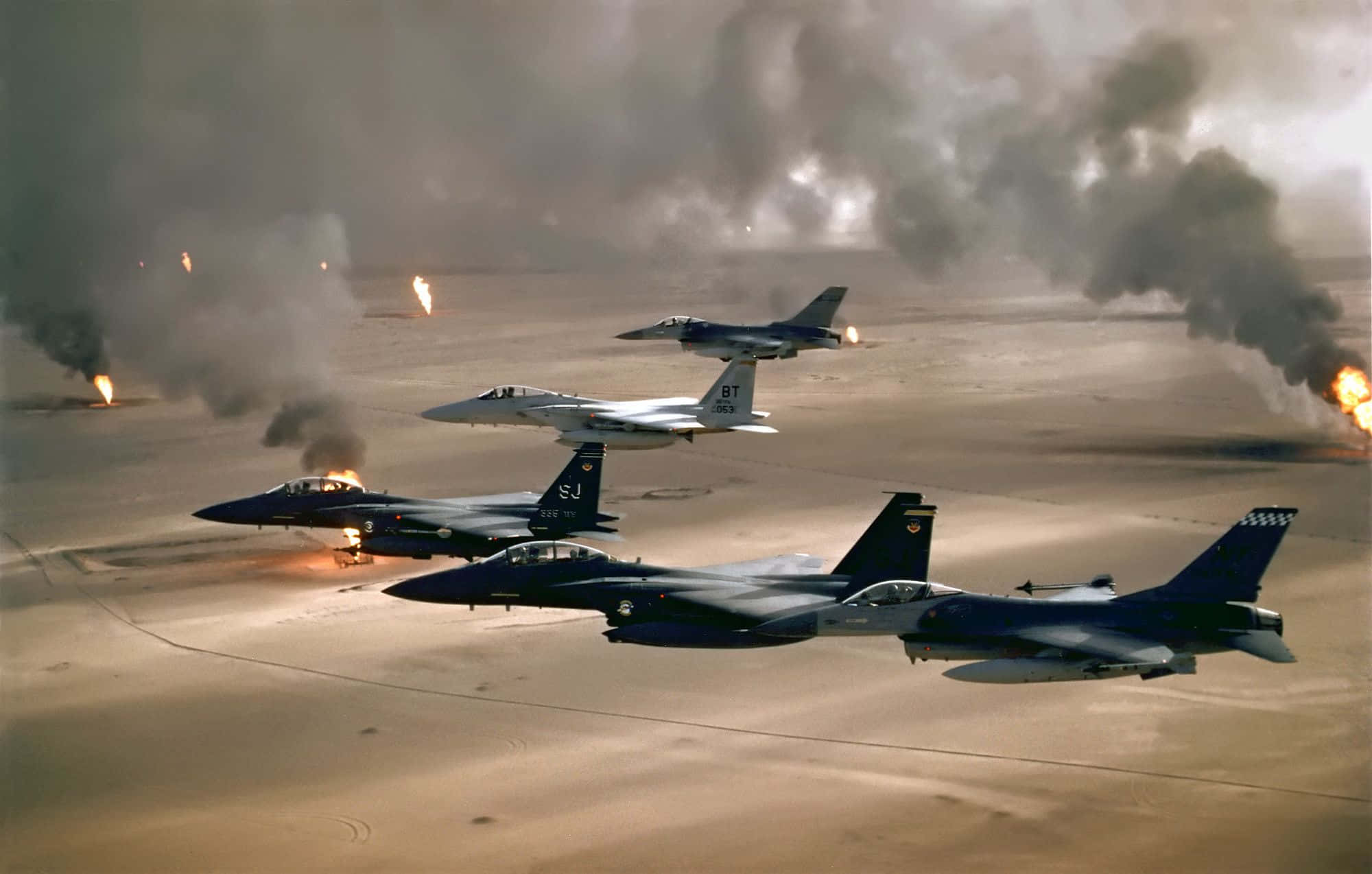 Air Force 桌布 壁紙 — 四架戰鬥機在沙漠戰場上空翱翔，下方燃燒的油井升起爆炸和濃煙。