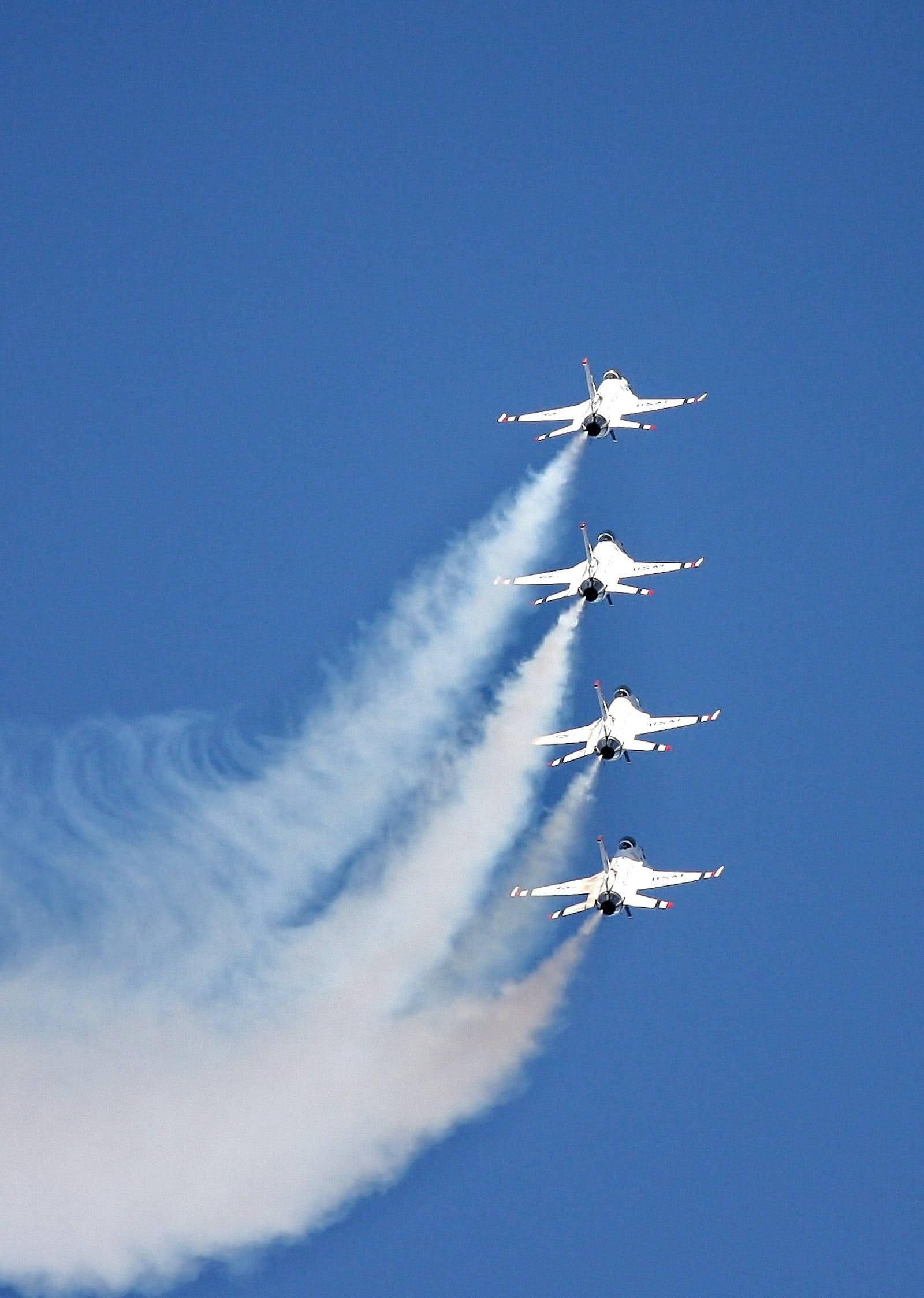 Air Force 桌布 壁紙 — 四架白色戰鬥機在晴朗的藍天下以緊密編隊飛行，留下濃厚的白色煙跡。