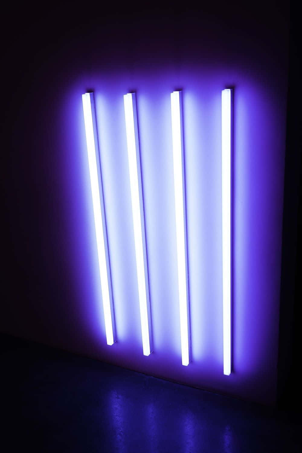 Fluorescent 桌布 壁紙 — 四根發光的紫色霓虹燈管在極簡現代藝術裝置中，向黑暗的牆壁投射出耀眼的光芒。