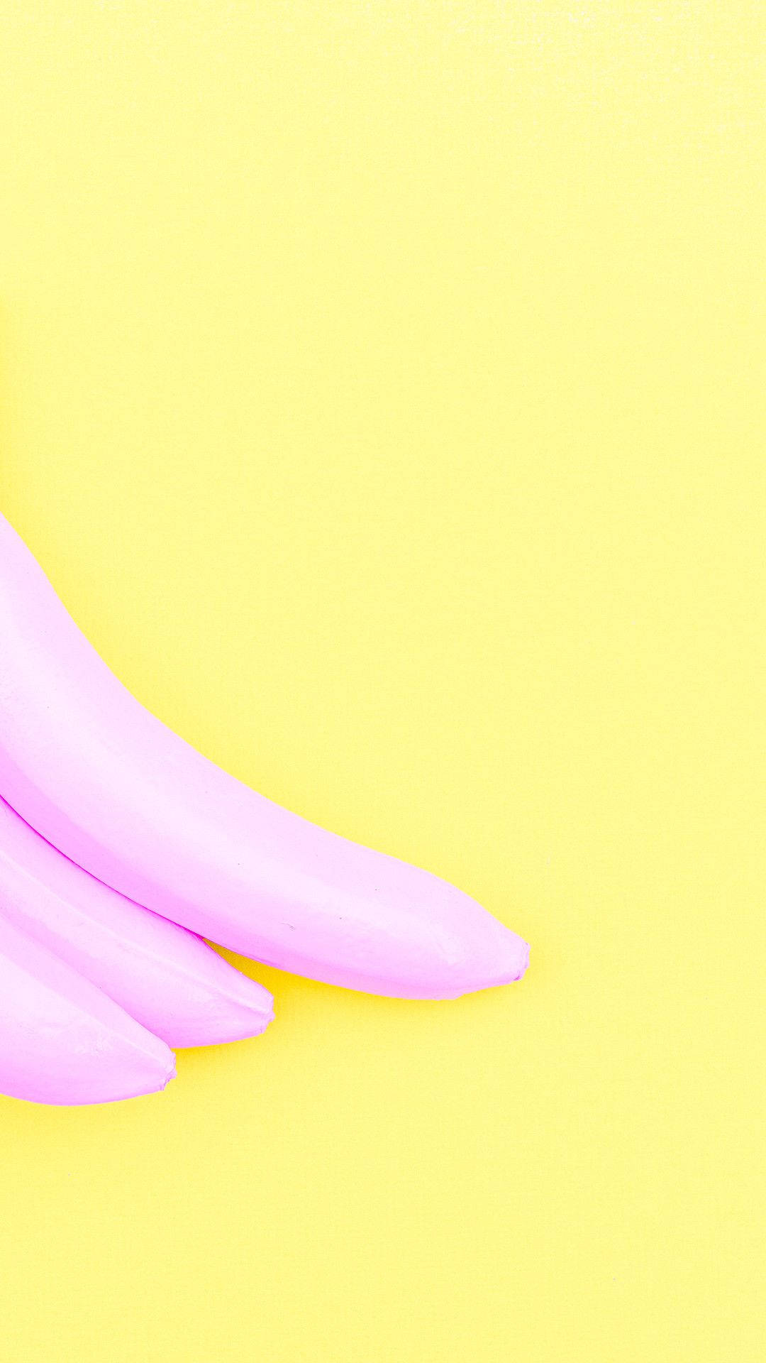 Pastel Yellow Aesthetic 桌布 壁紙 — 四條粉紅色香蕉在明亮的黃色背景上對角彎曲，呈現極簡主義的平面佈局。