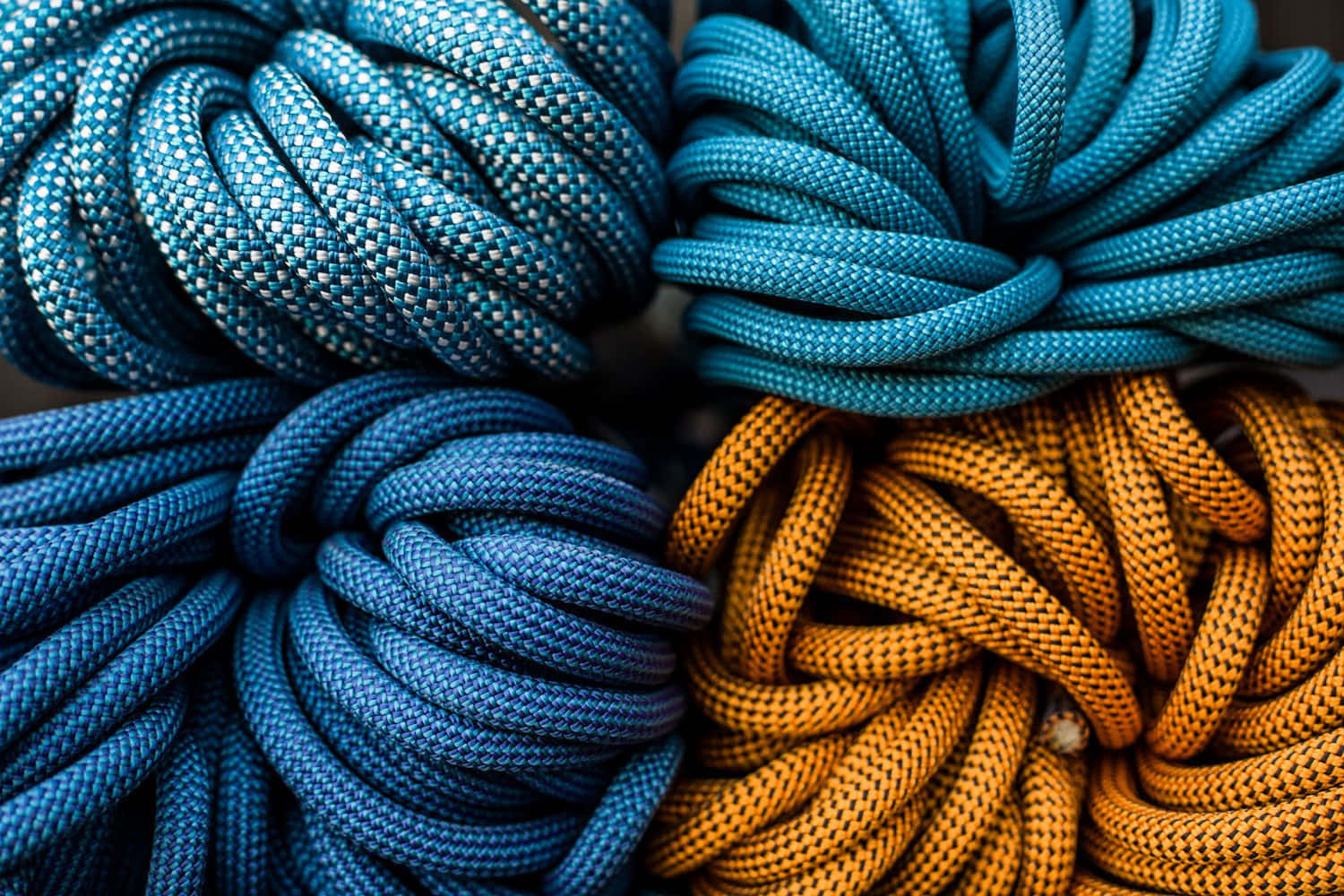 Climbing 桌布 壁紙 — 四條藍色和橙色色調的盤繞繩索特寫，展示出紋理編織圖案和鮮豔色彩。