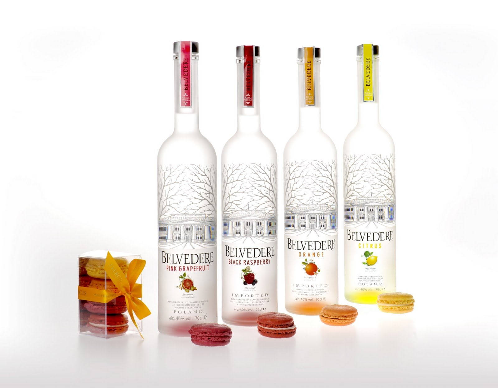 alcohol 桌布 壁紙 — 四瓶Belvedere伏特加，口味分別為粉紅葡萄柚、黑覆盆子、橙和柑橘，旁邊擺放著色彩繽紛的馬卡龍，置於潔白表面上。