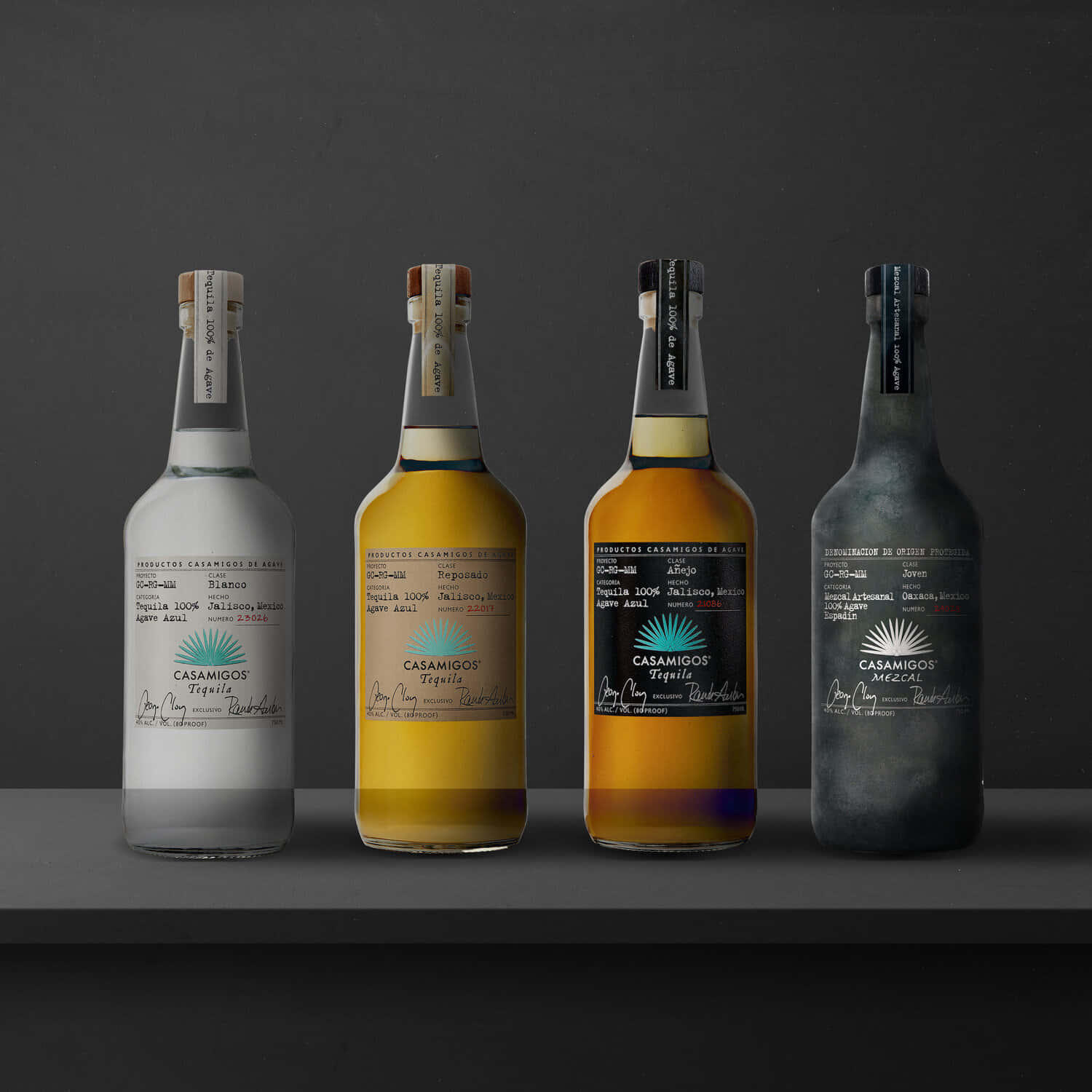 alcohol 桌布 壁紙 — 四瓶不同顏色的 Casamigos 龍舌蘭酒整齊排列在深色架子上，背景為柔和的灰色。
