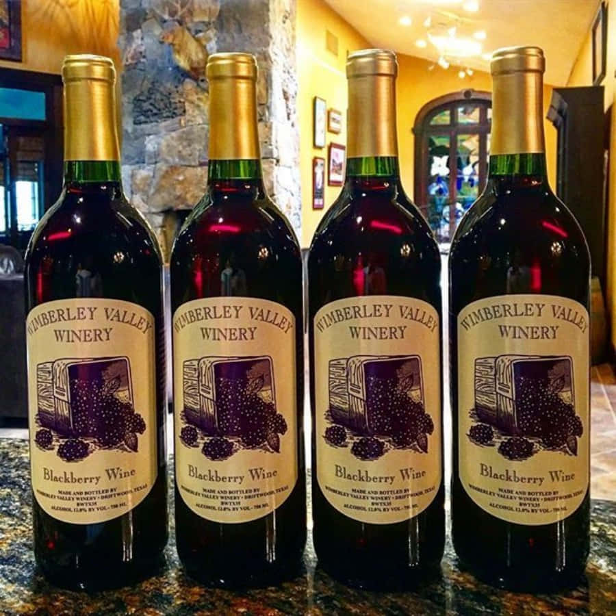 Blackberry Wine 桌布 壁紙 — 四瓶來自Timberley Valley Winery的黑莓酒整齊排列在花崗岩檯面上，處於溫暖燈光下的鄉村風格室內。
